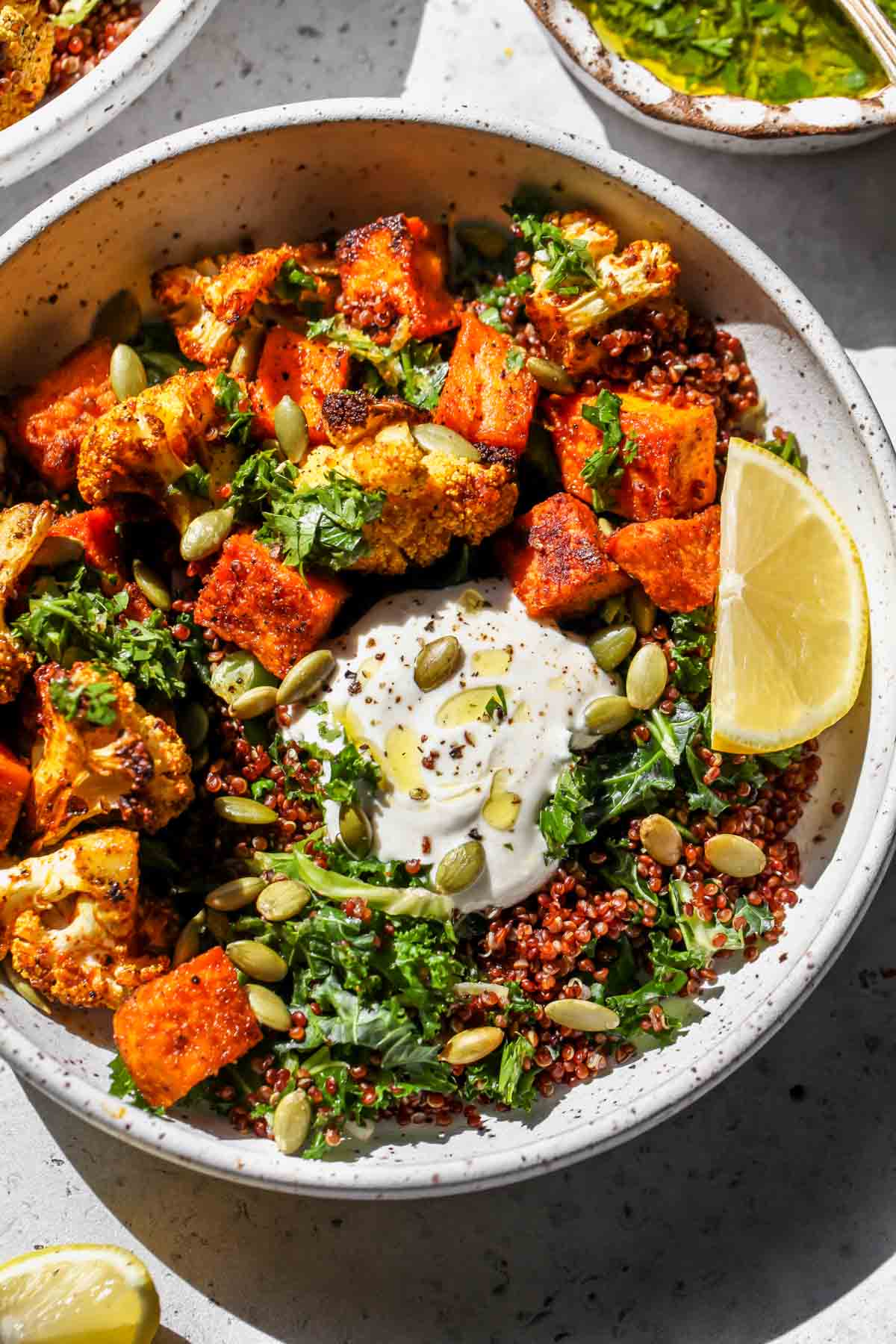 Curried cauliflower and sweet potato bowls assembled and topped with yogurt and pepitas
