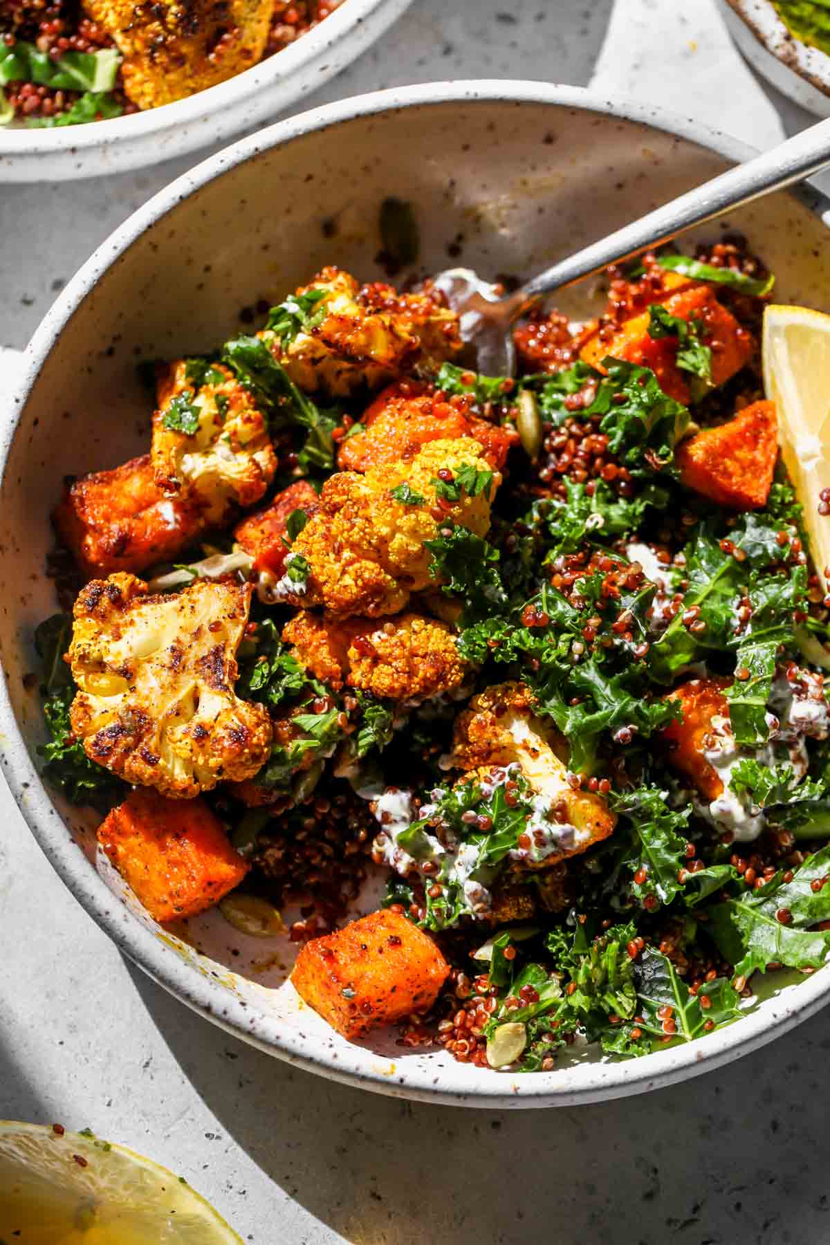 Curried cauliflower and sweet potato bowls with quinoa being mixed with a fork