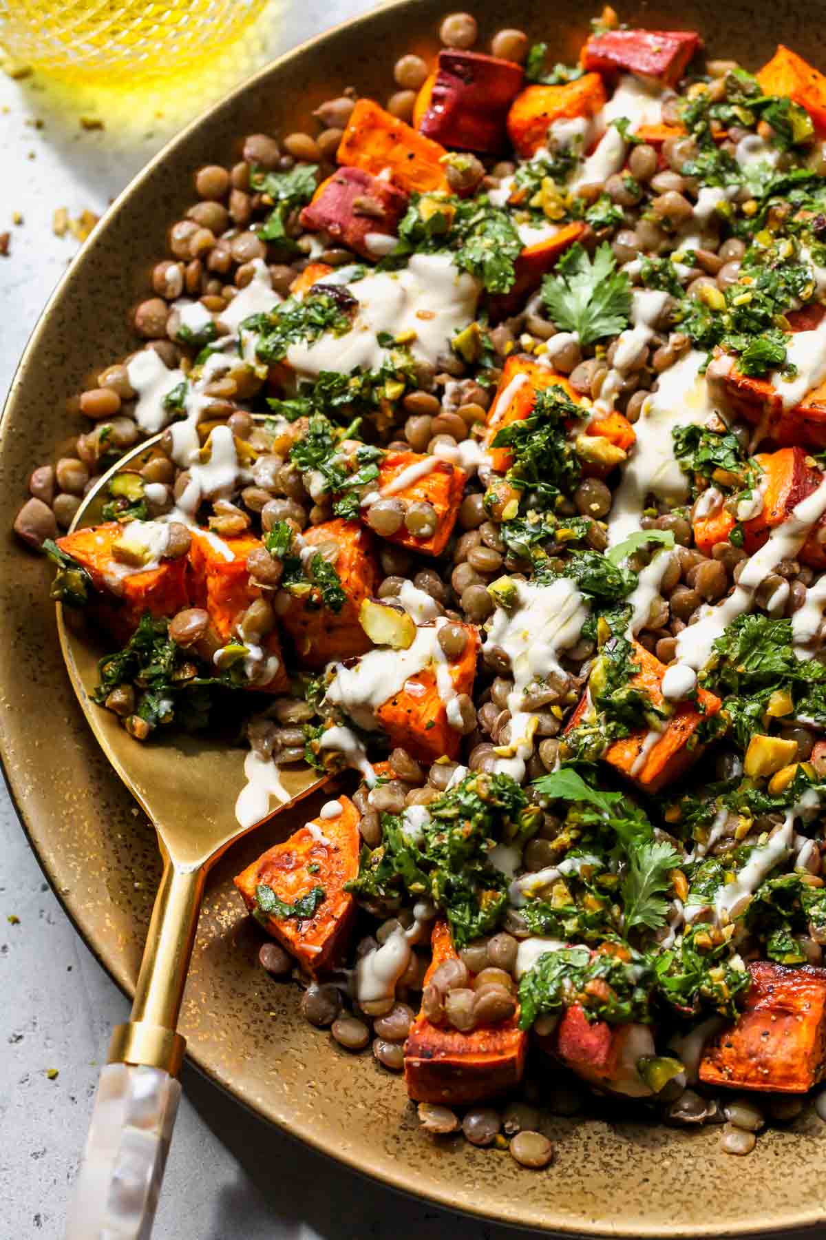 Vegan lentil salad being served with a gold serving spoon
