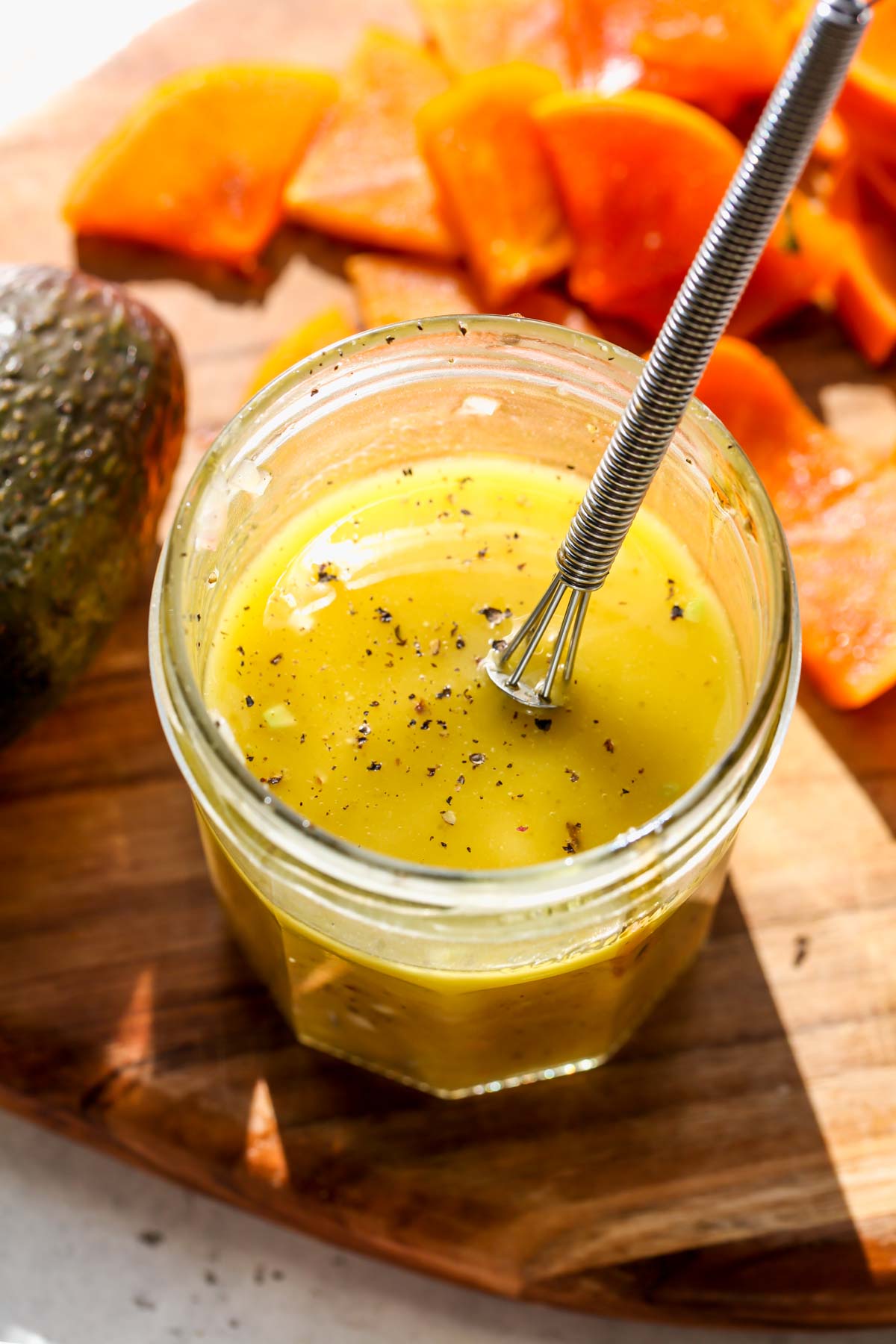 White wine vinaigrette in a jar with a small whisk resting on the side