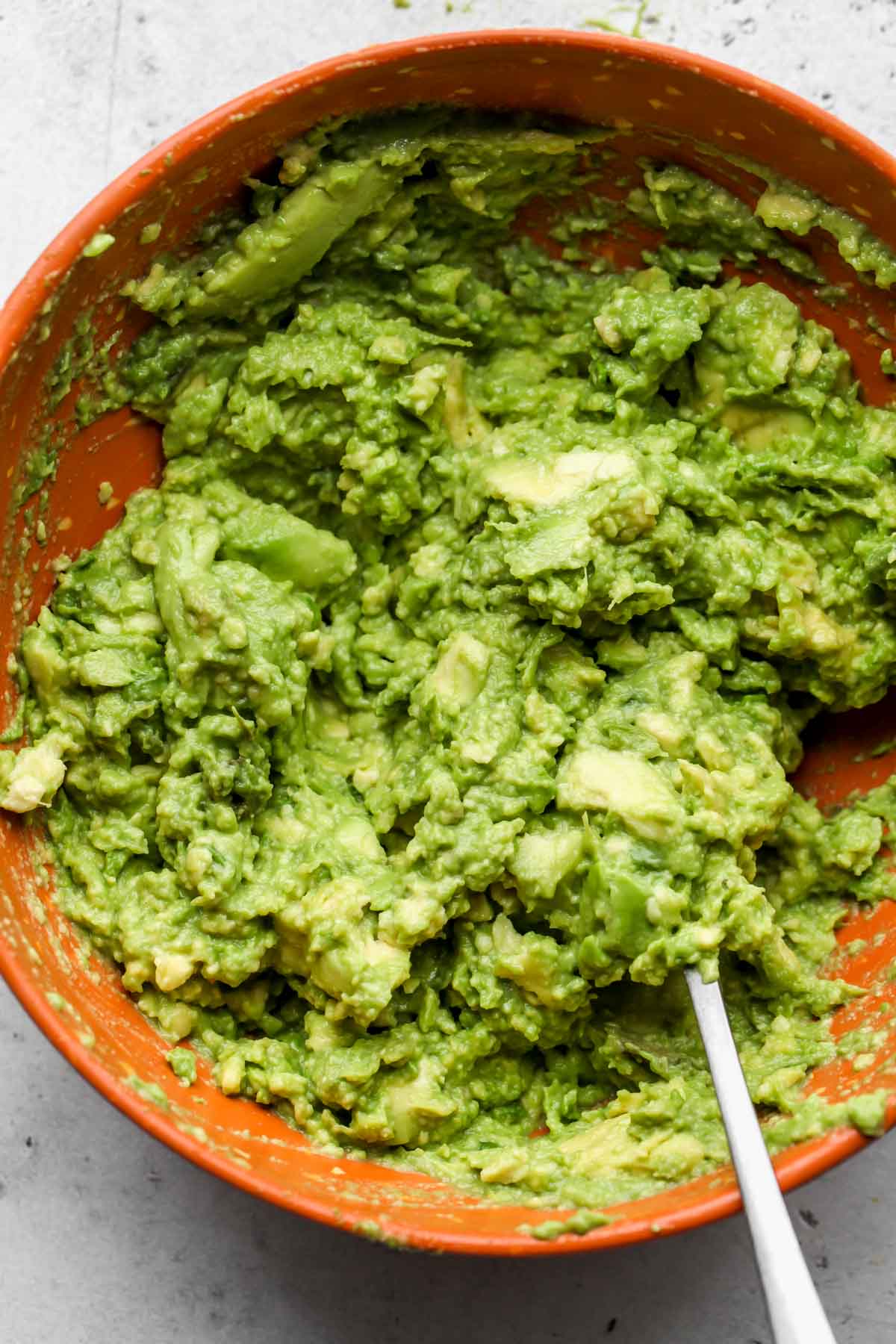 Avocado being mashed in a bowl with lemon juice and salt
