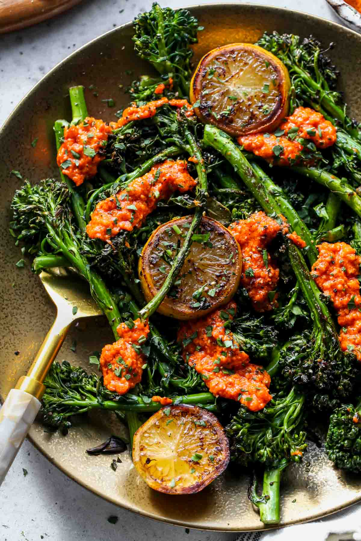 Charred broccoli topped with hazelnut romesco and lemon on a gold serving platter