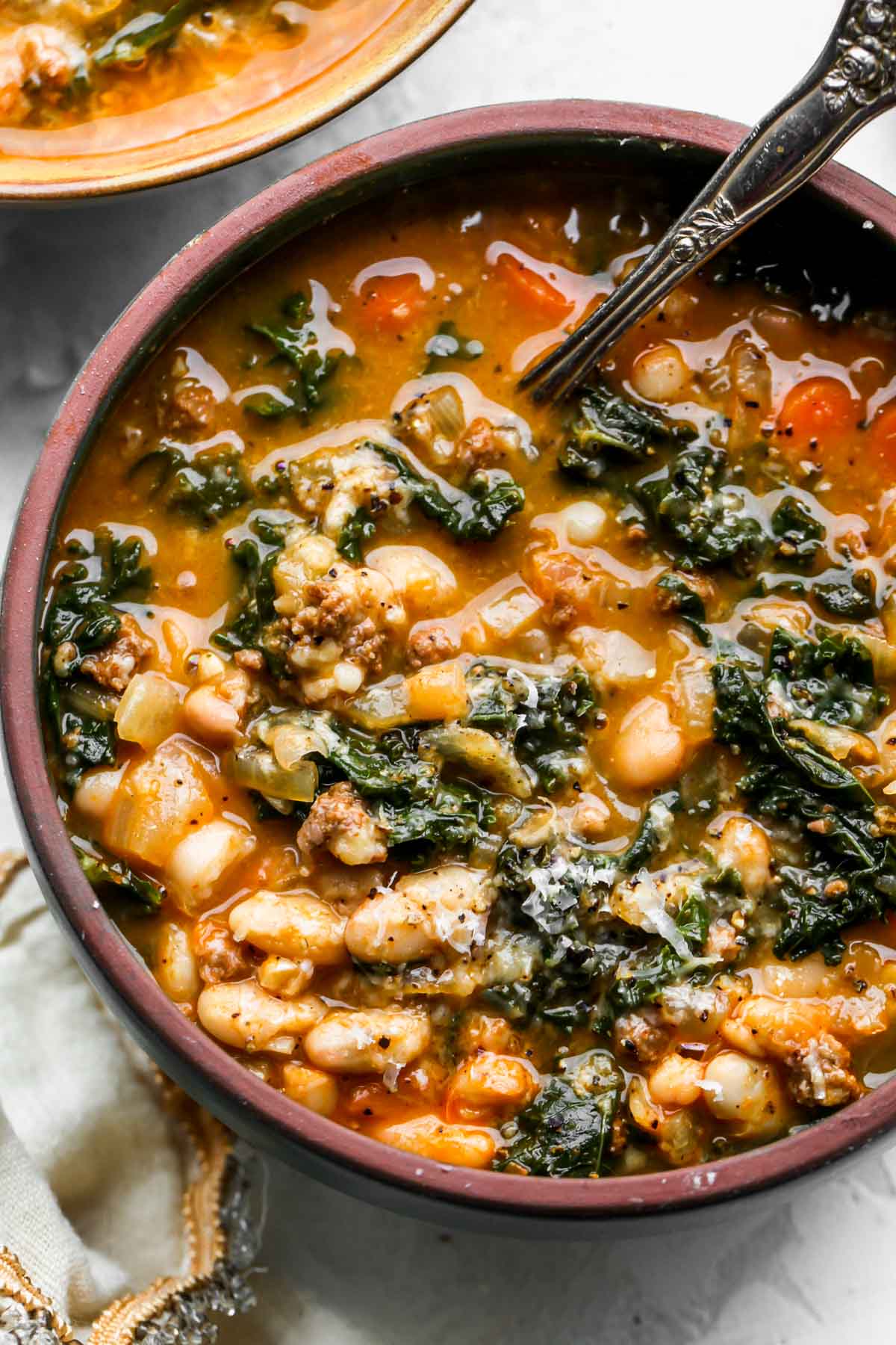 Chorizo white bean soup in a blue bowl with a spoon resting on the right side