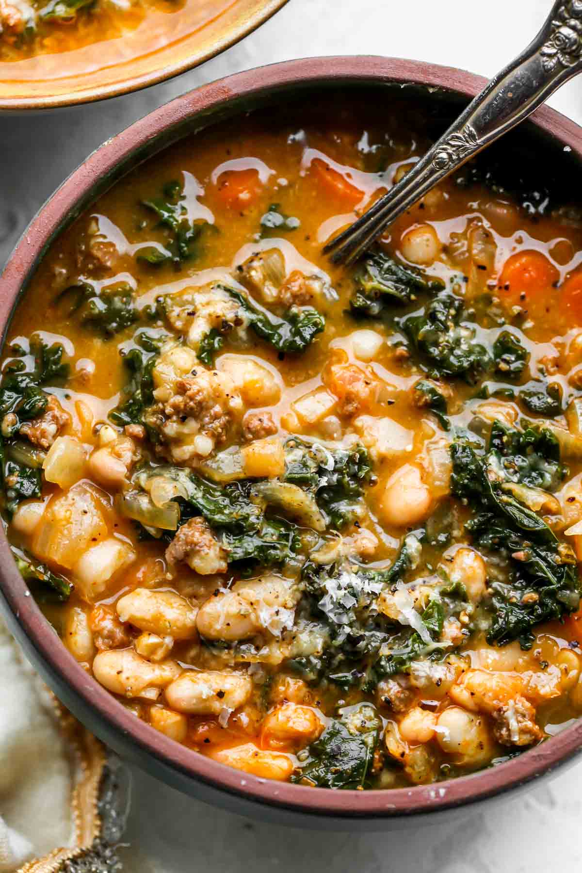Chorizo white bean soup in a bowl with a spoon resting on the edge