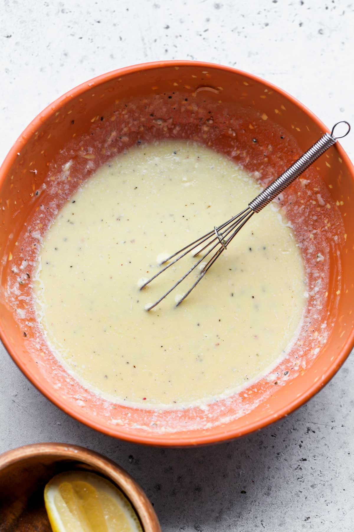 Parmesan Peppercorn dressing being whisked in an orange bowl
