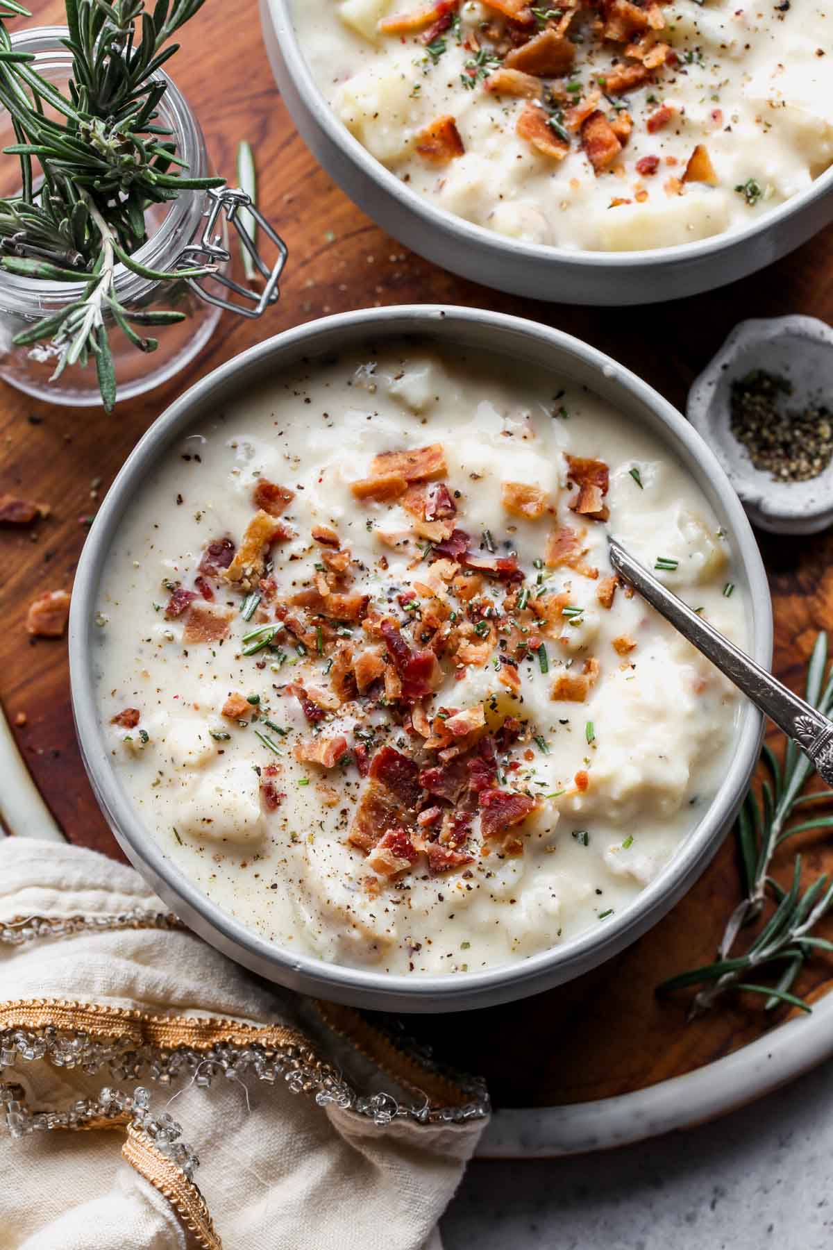 A bowl of slow cooker potato soup on a wooden serving platter