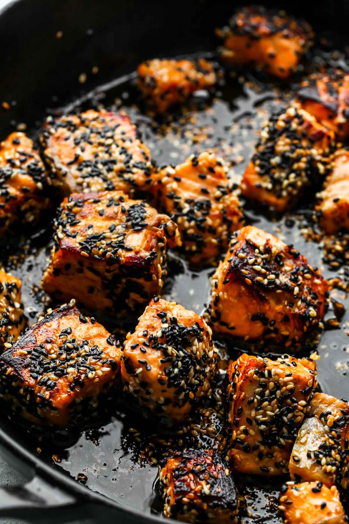 Salmon cubes being sauteed in a cast iron skillet until golden