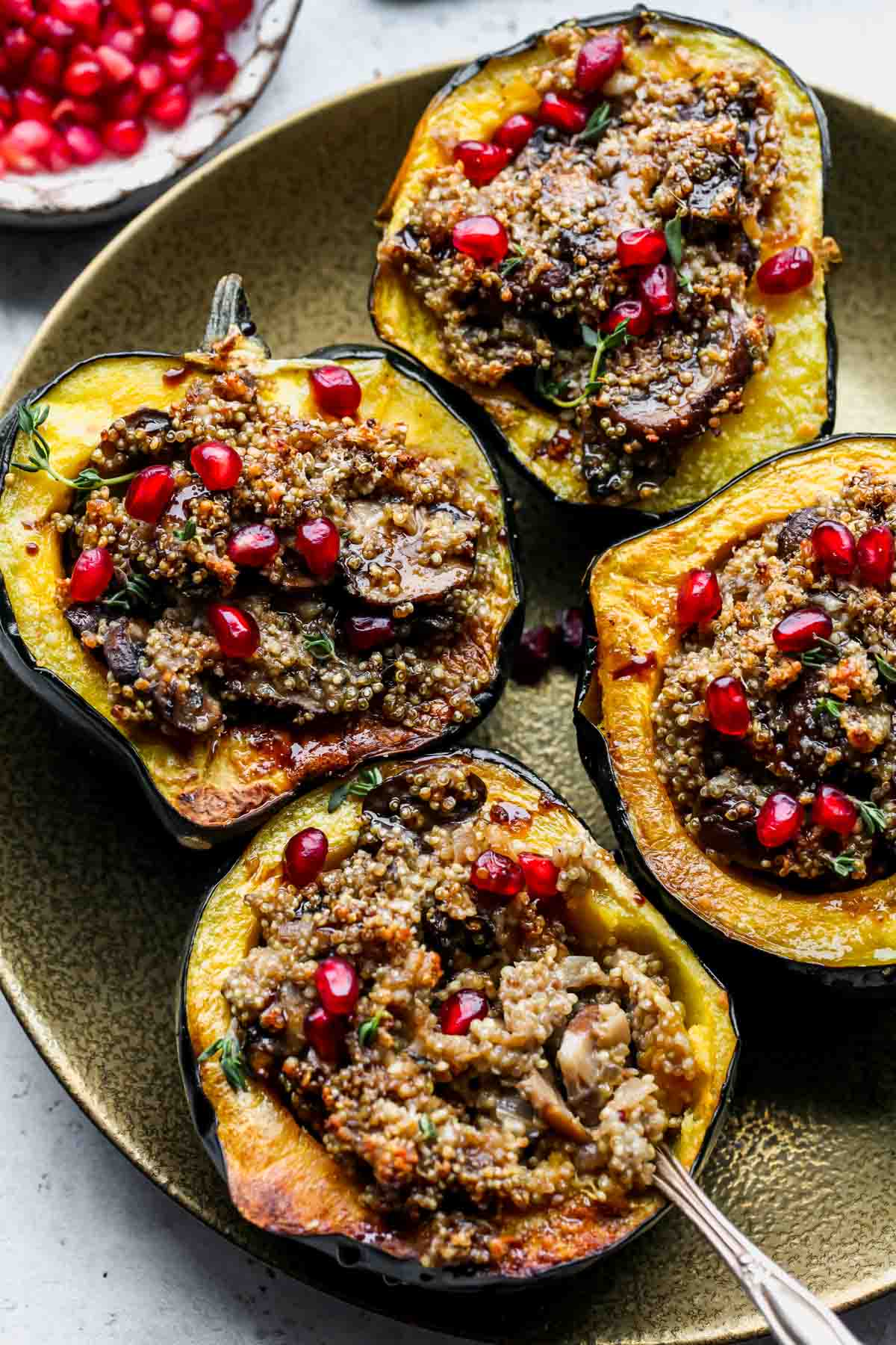 Quinoa stuffed acorn squash halves arranged on a gold serving platter
