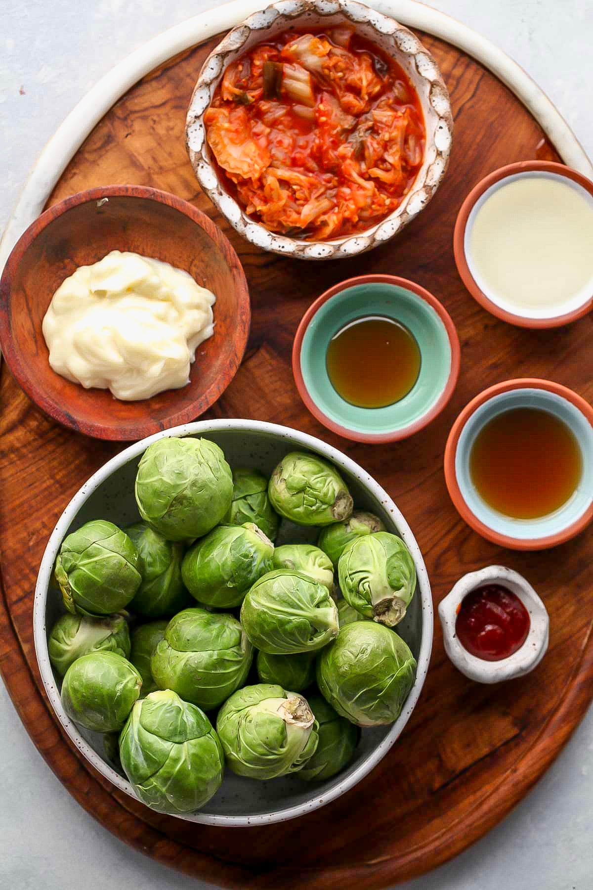 Recipe ingredients in bowls arranged on a wooden serving platter