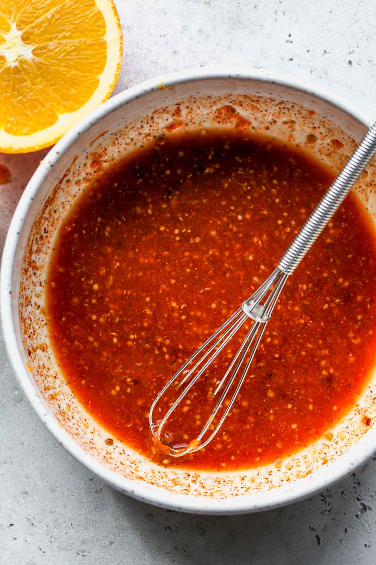Orange maple mixture being whisked in a white bowl