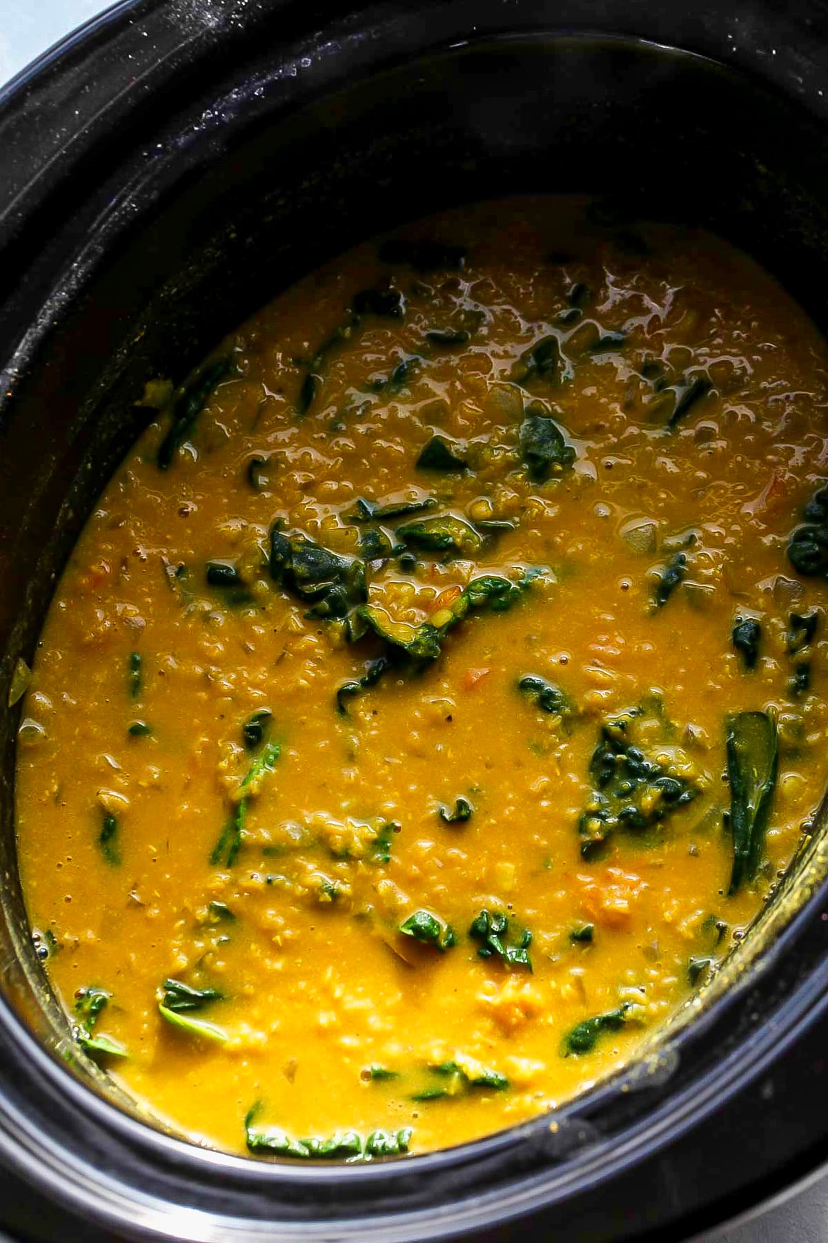 Soup in the crockpot after kale and coconut milk are mixed in