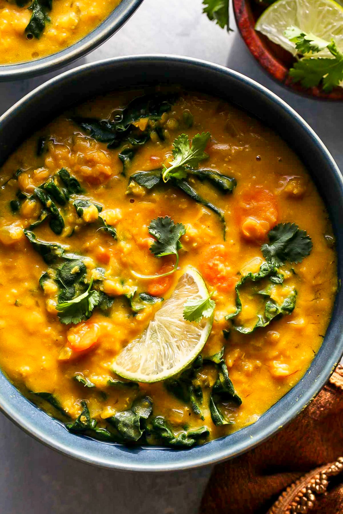 Slow Cooker Golden Lentil Soup topped with cilantro and a lime wedge