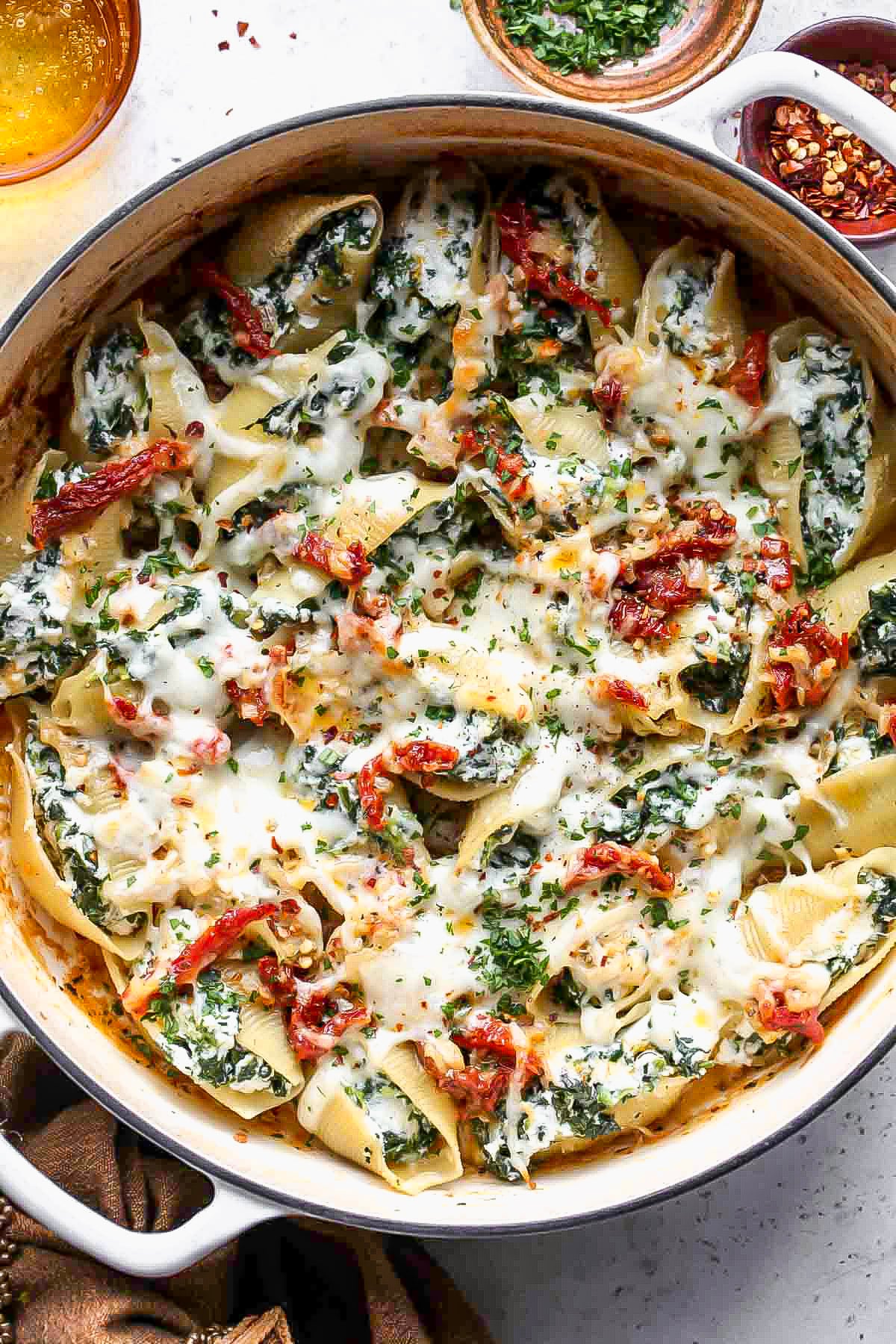 Ricotta stuffed shells in topped with sun-dried tomato sauce and mozzarella in a baking dish