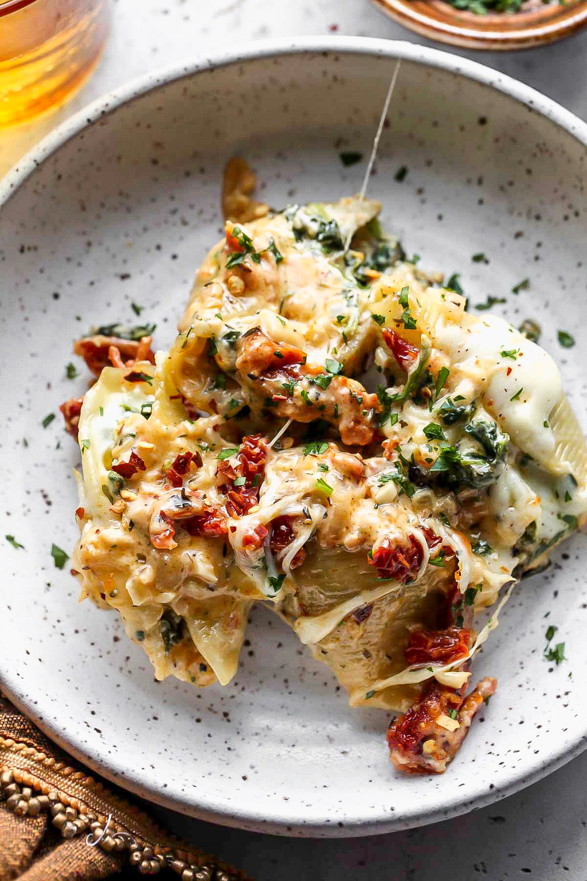 Single serving of stuffed shells on a white speckled dinner plate