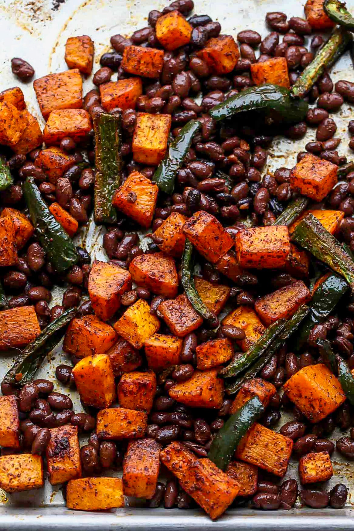 Roasted squash, black beans, and peppers coated in spices on a sheet pan.