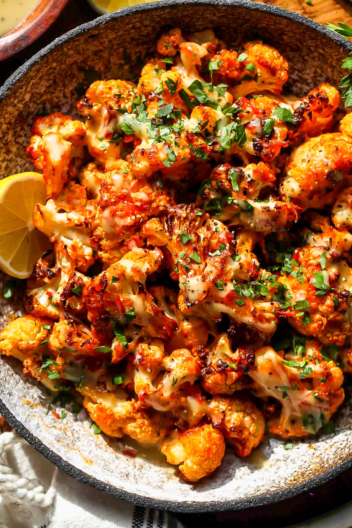 Roasted cauliflower drizzled with tahini honey in a gray serving bowl