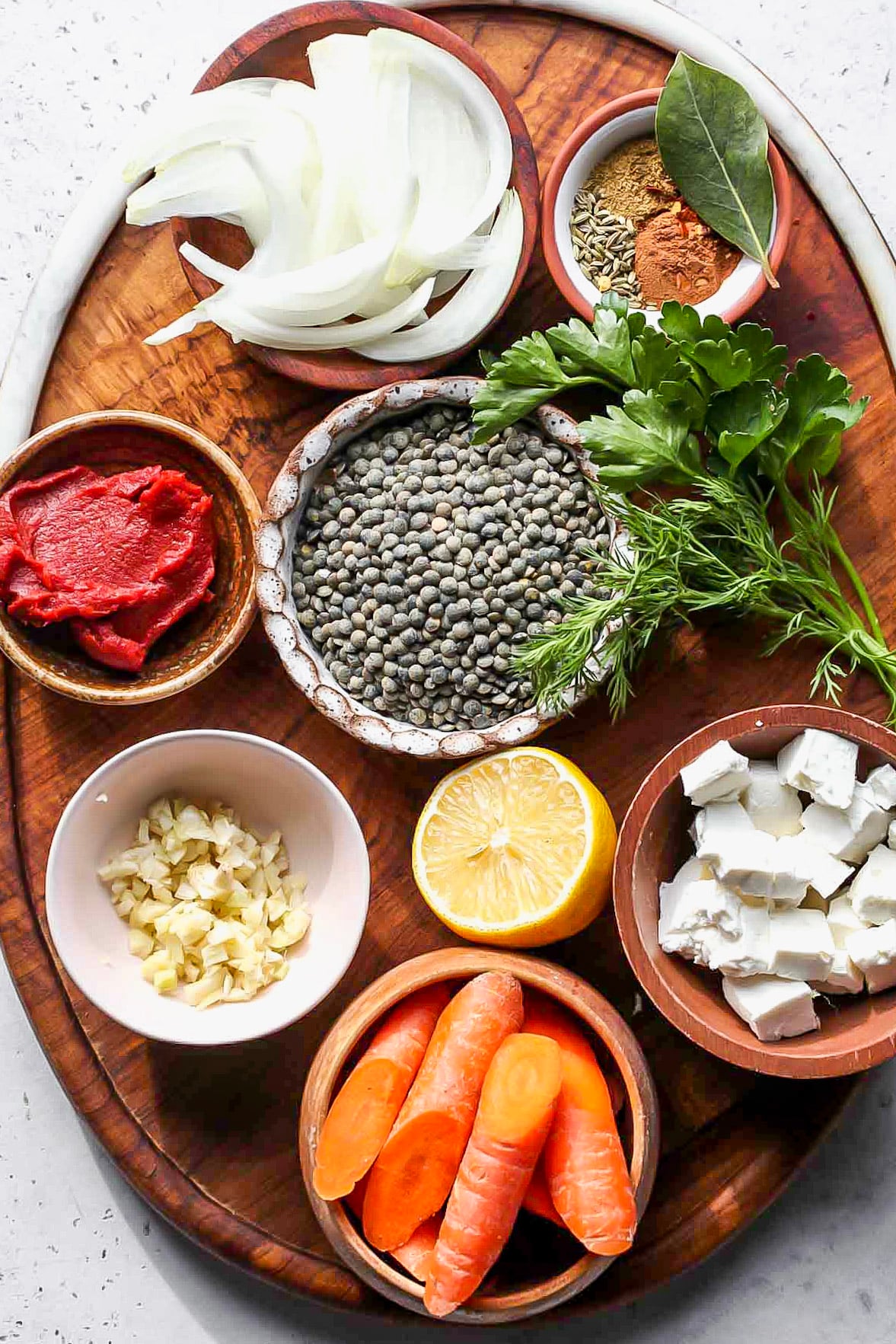 Recipe ingredients in separate bowls arranged on a wooden serving platter