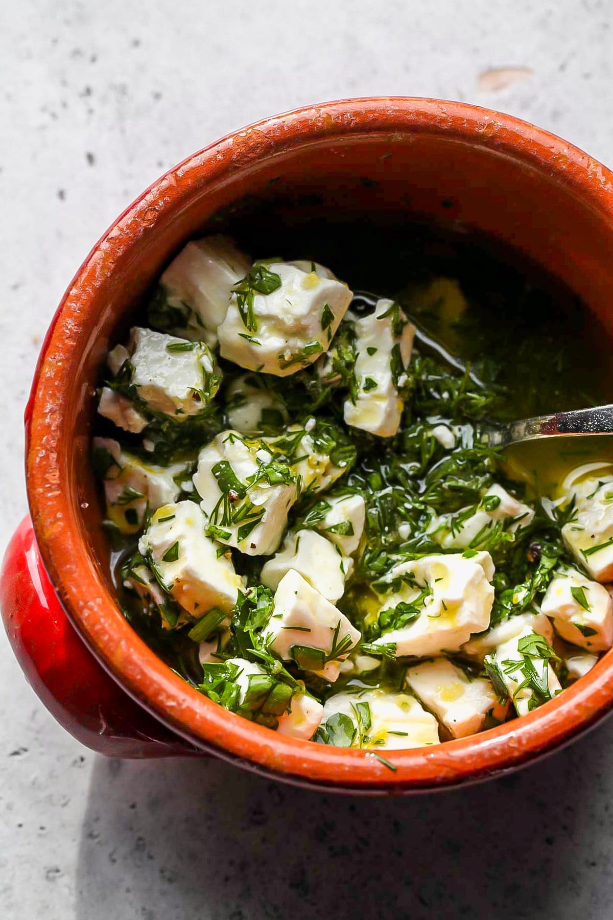 Marinated feta being mixed in a red bowl