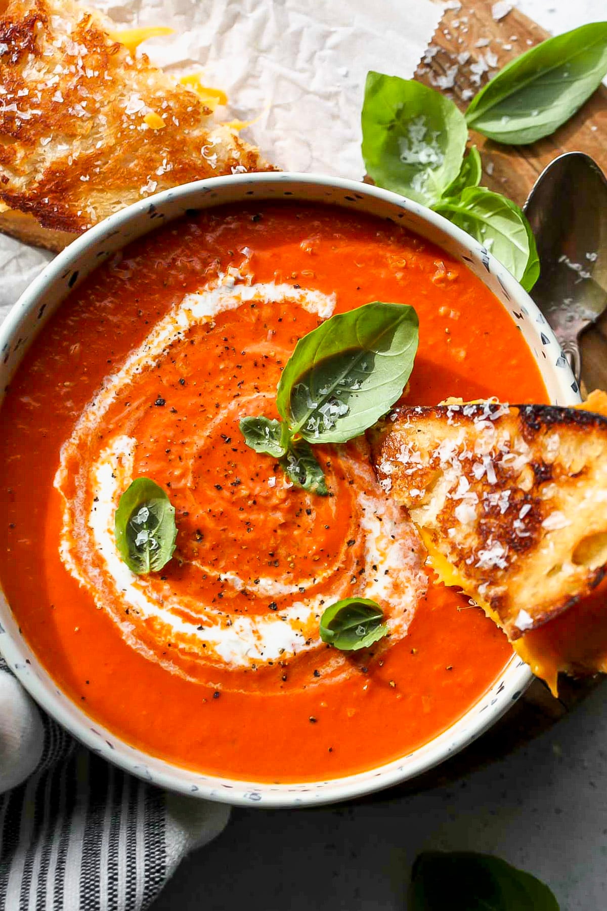Half of a grilled cheese sandwich being dunked in a bowl of easy tomato soup