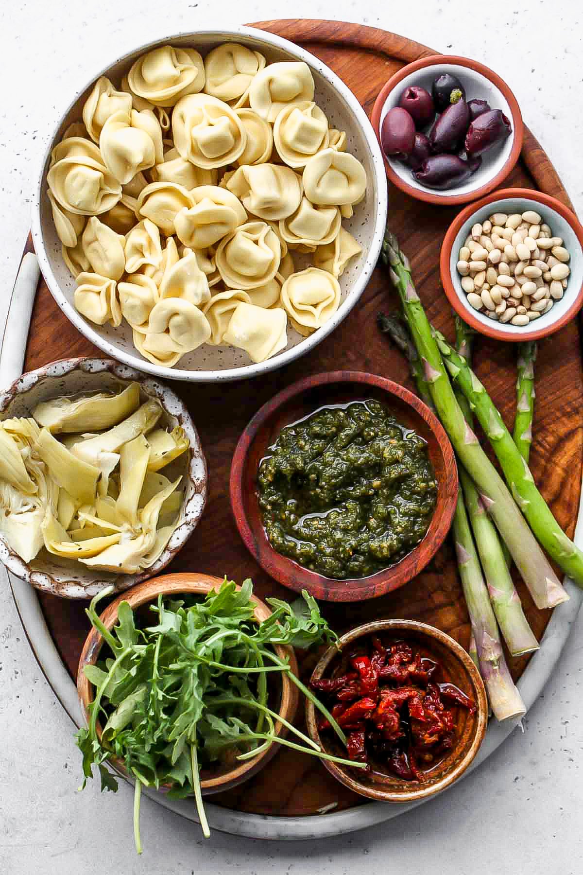 Recipe ingredients in separate bowls arranged on a wooden serving platter