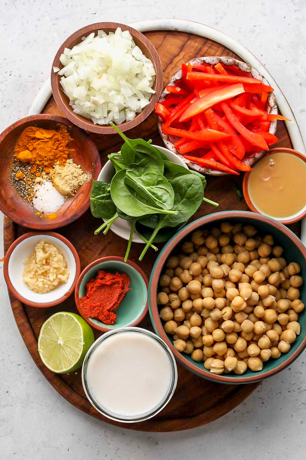Recipe ingredients in separate bowls arranged on a wooden serving platter