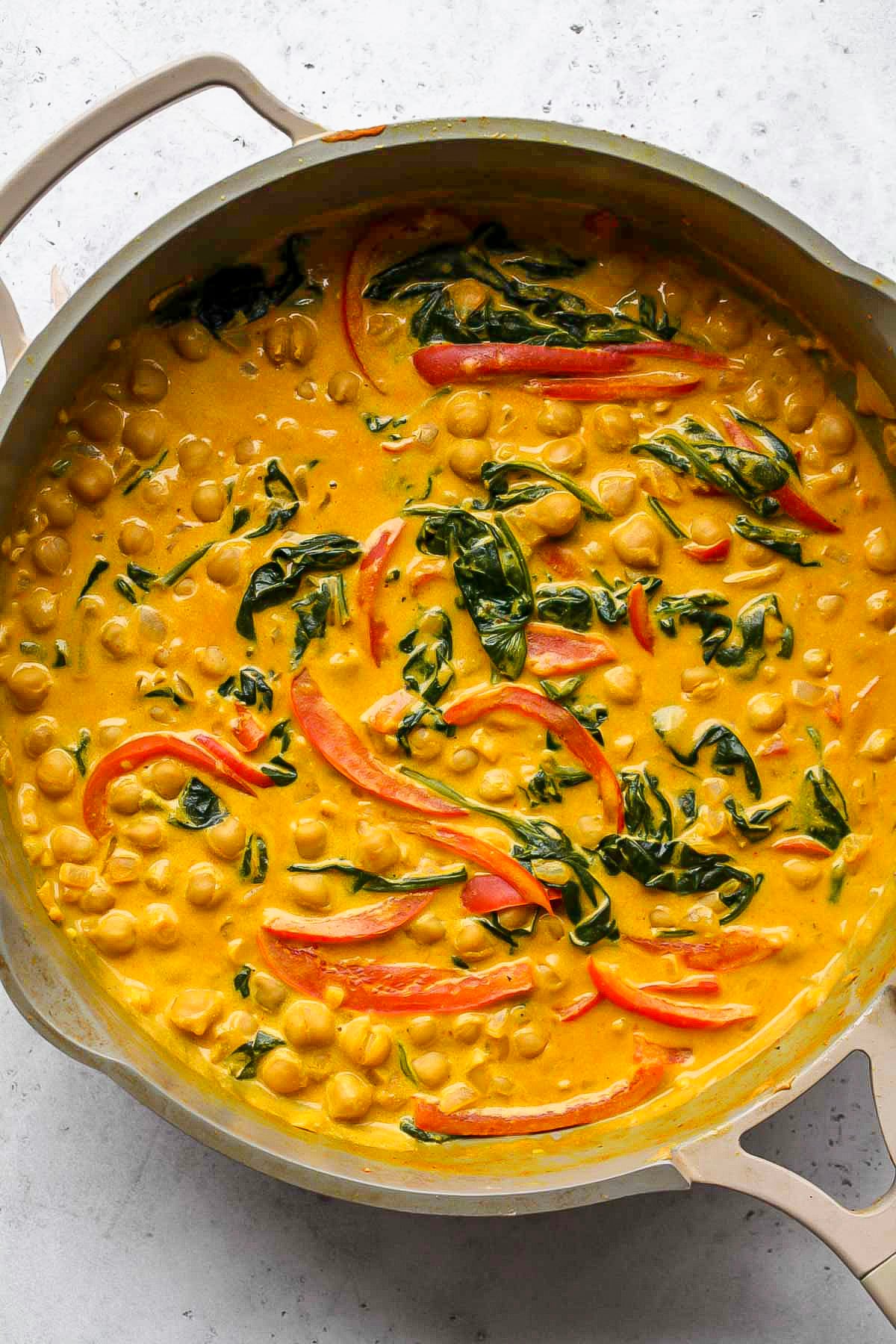 Milk and peanut butter being added to curry, and simmering until thickened