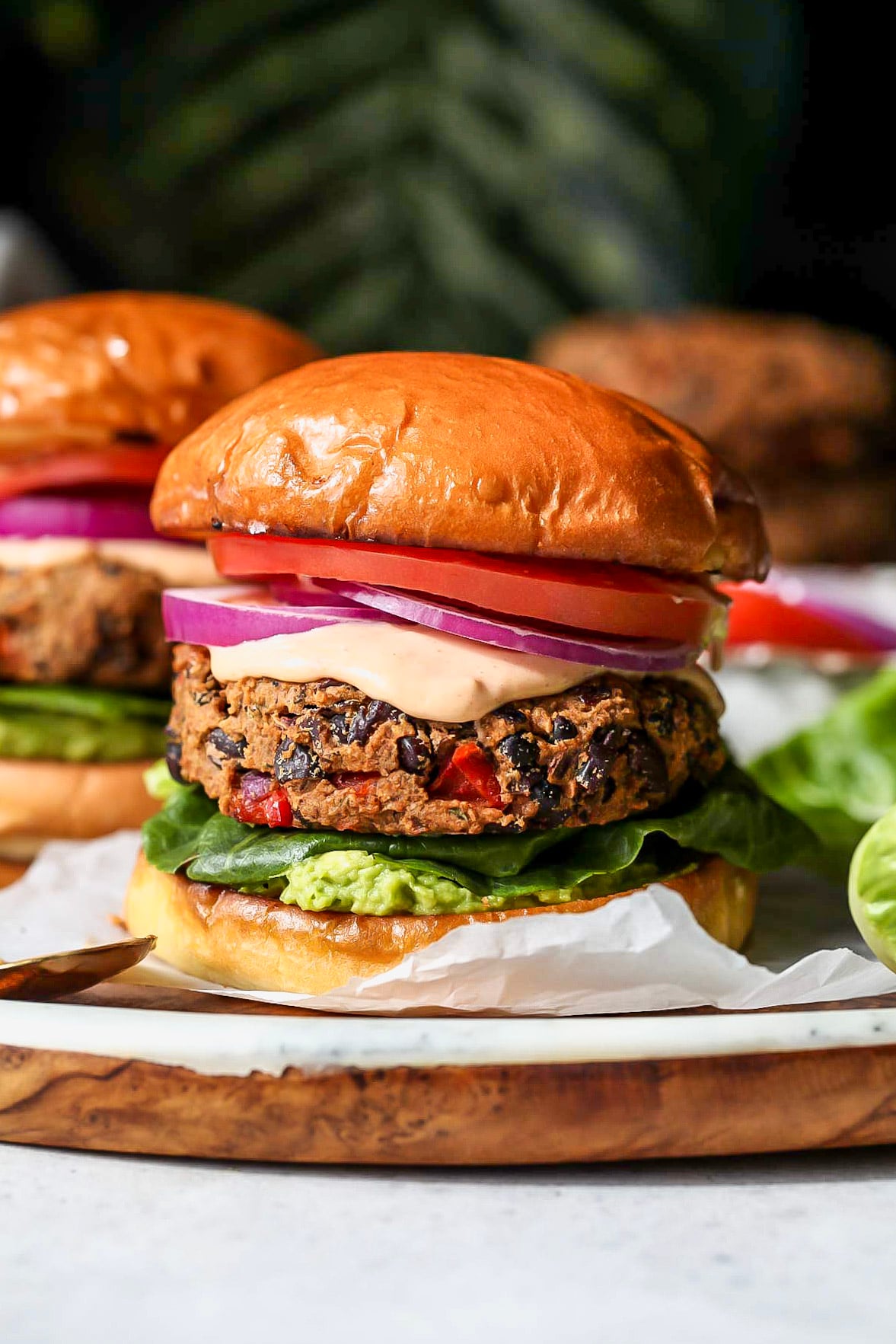 Chipotle black bean burgers with toppings arranged on a wooden serving platter.