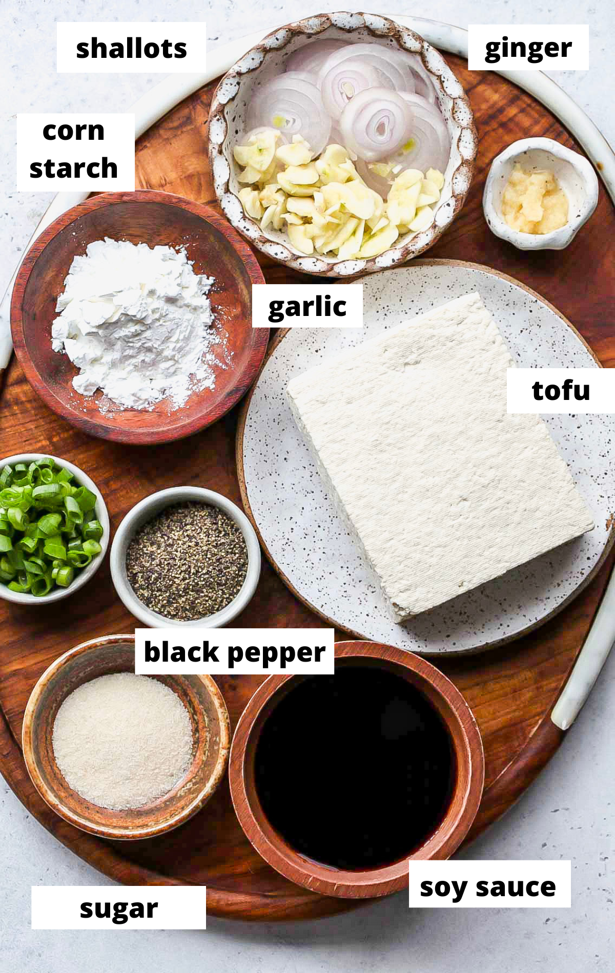 Black Pepper Tofu Recipe ingredients in bowls arranged on a wooden board with labels.