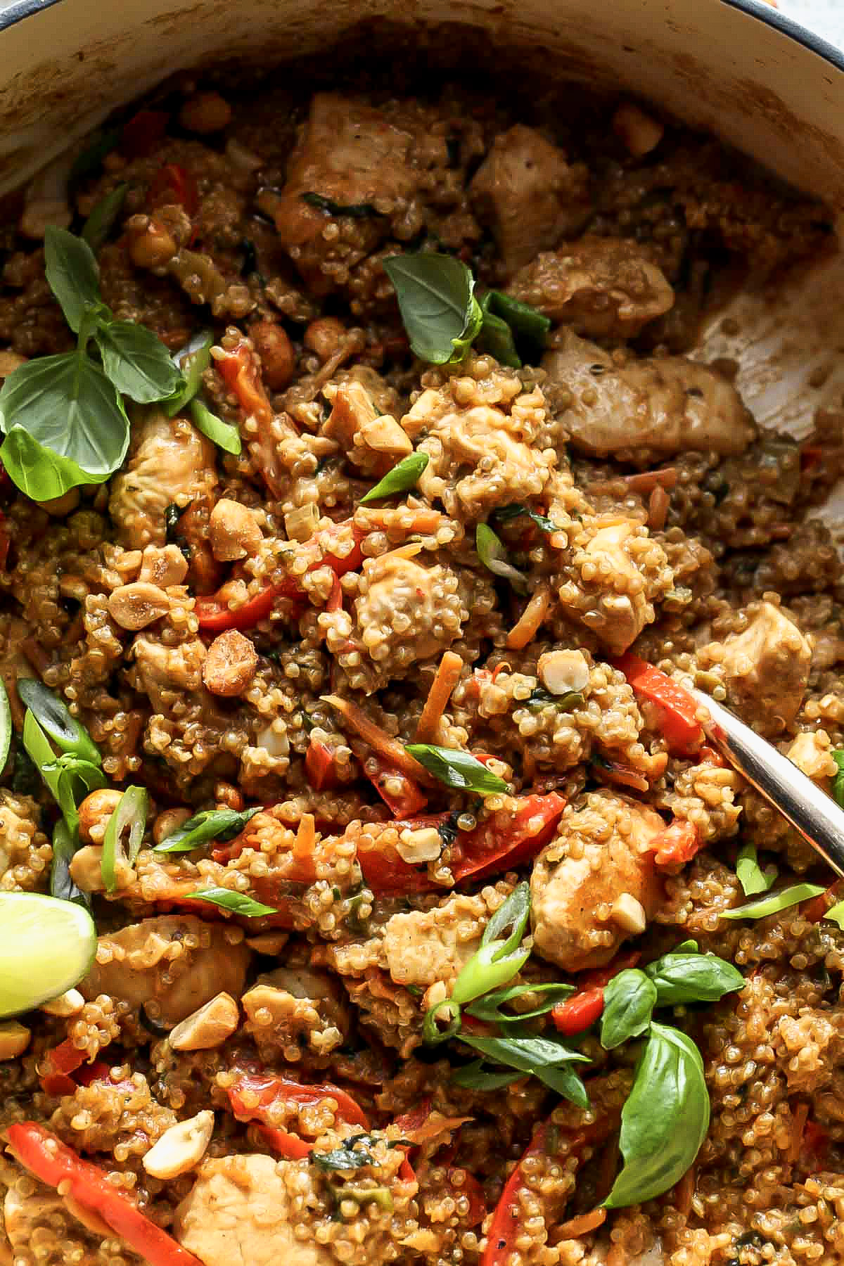 Peanut chicken and quinoa being scooped up with a gold serving spoon