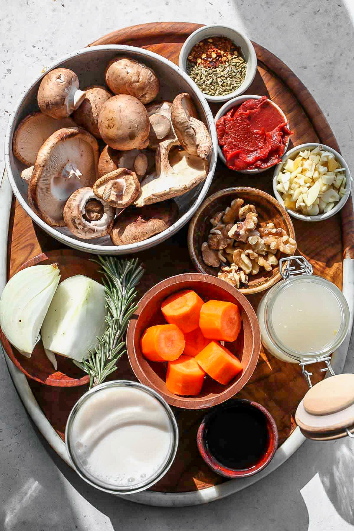 Recipe ingredients in separate bowls arranged on a wooden serving platter.