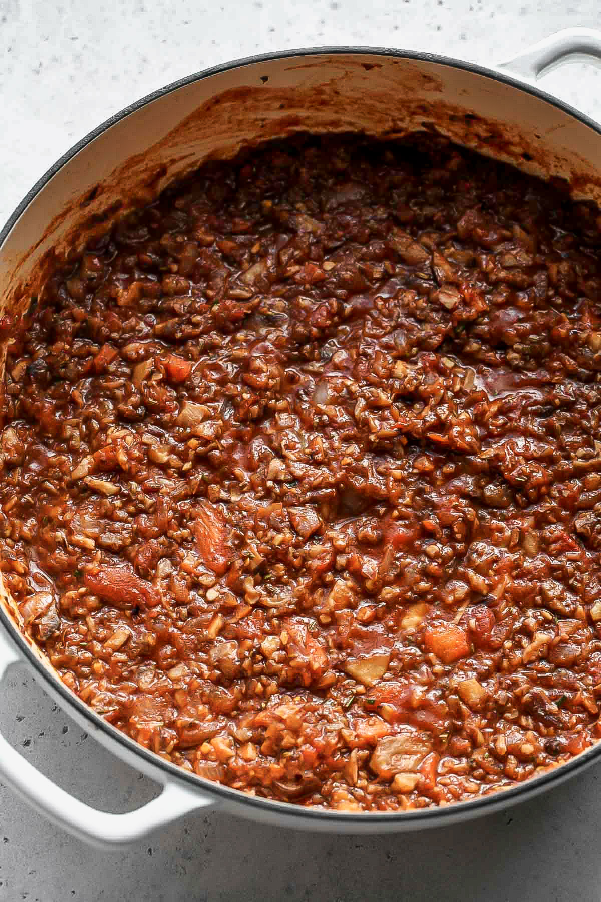 A large white pot filled with bolognese sauce after being simmered.
