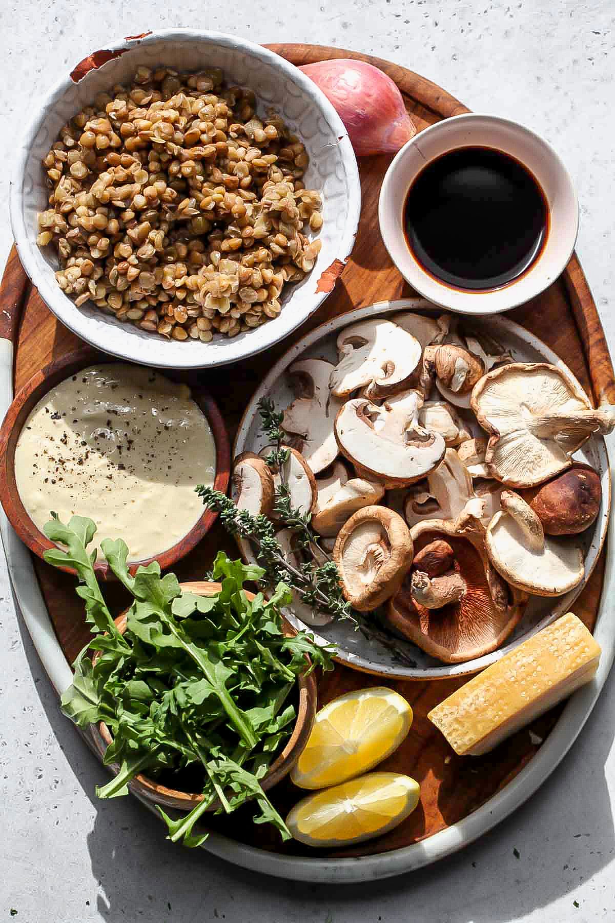 Recipe ingredients in separate bowls arranged on a wooden serving platter.