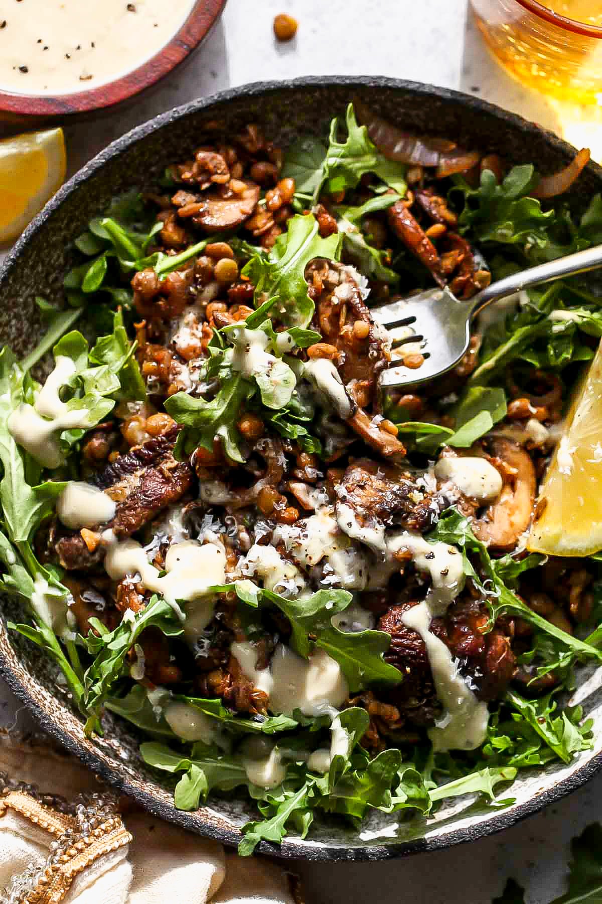 A fork digging into a bowl of warm lentil salad.