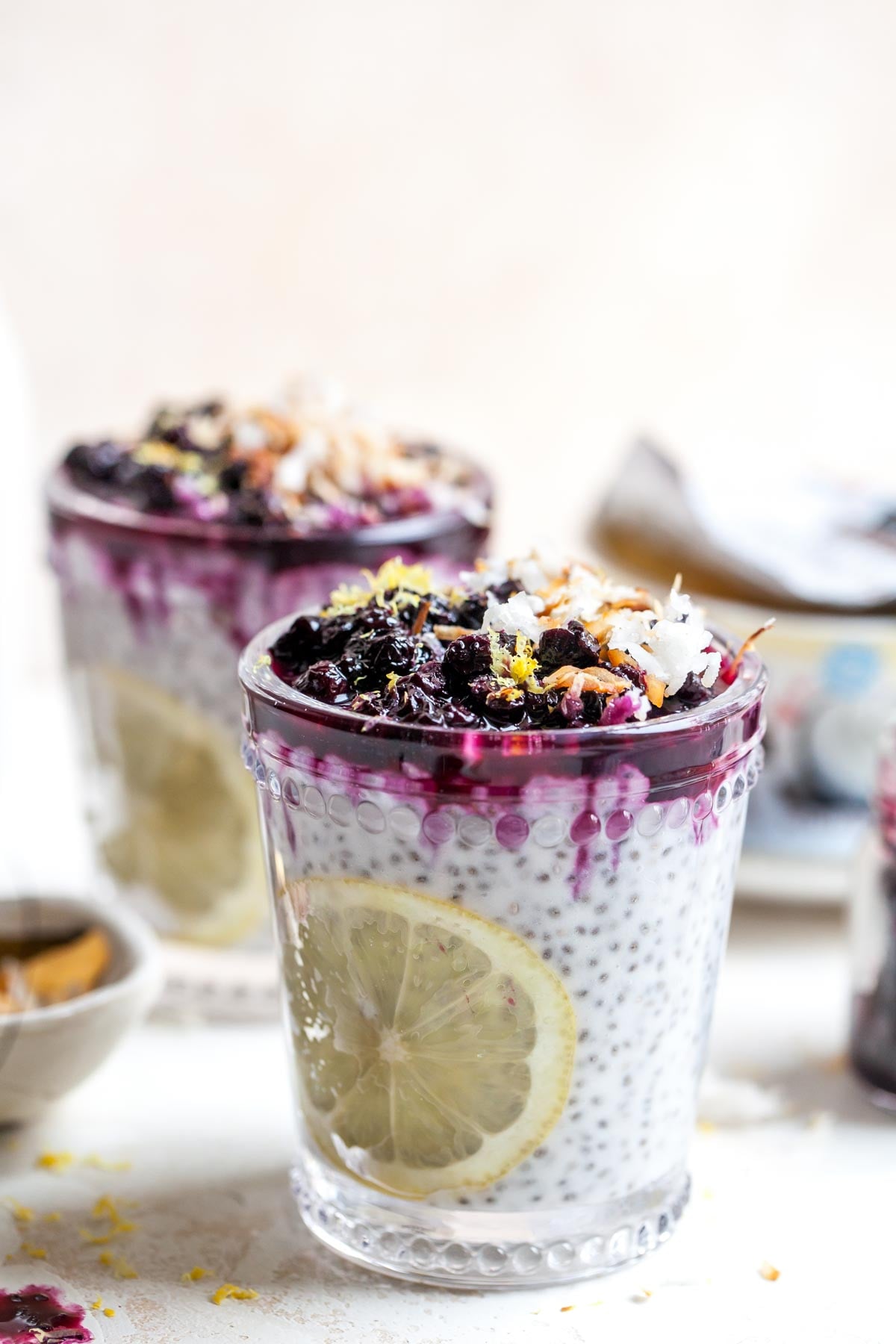 Coconut chia pudding in a clear glass topped with blueberry compote.