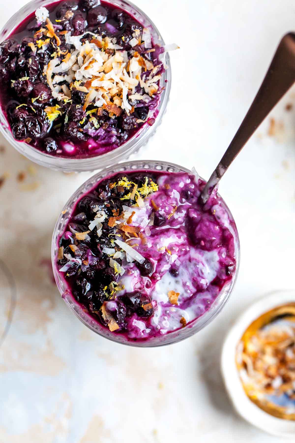 A spoon digging into a glass jar filled with coconut chia pudding.