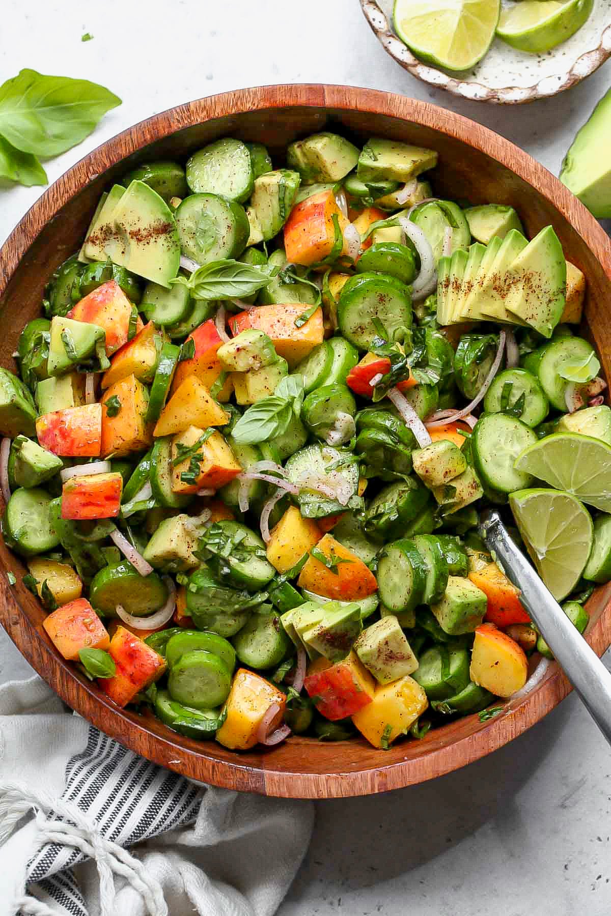 Cucumber peach salad in a wooden serving bowl.