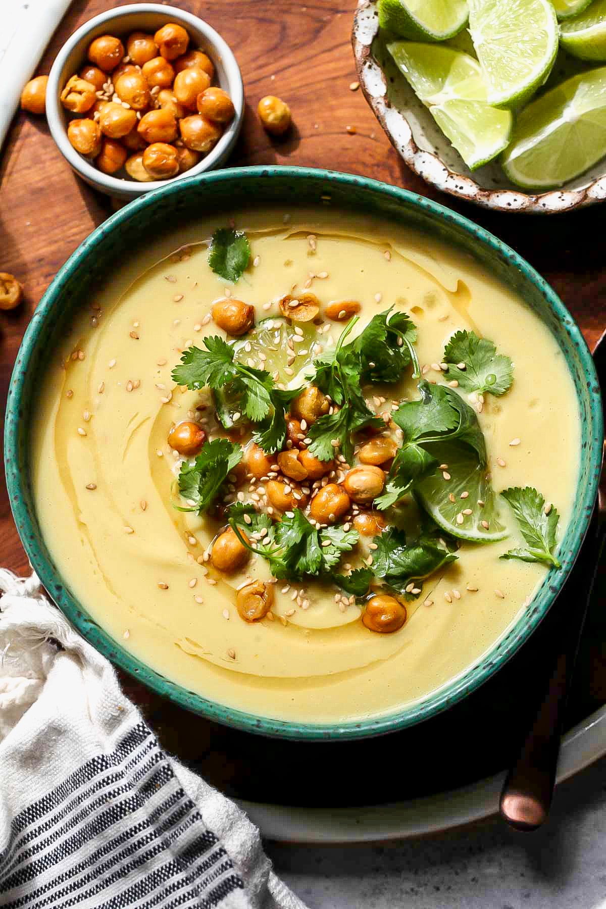 Curried cauliflower soup in a teal bowl topped with chickpeas and cilantro.