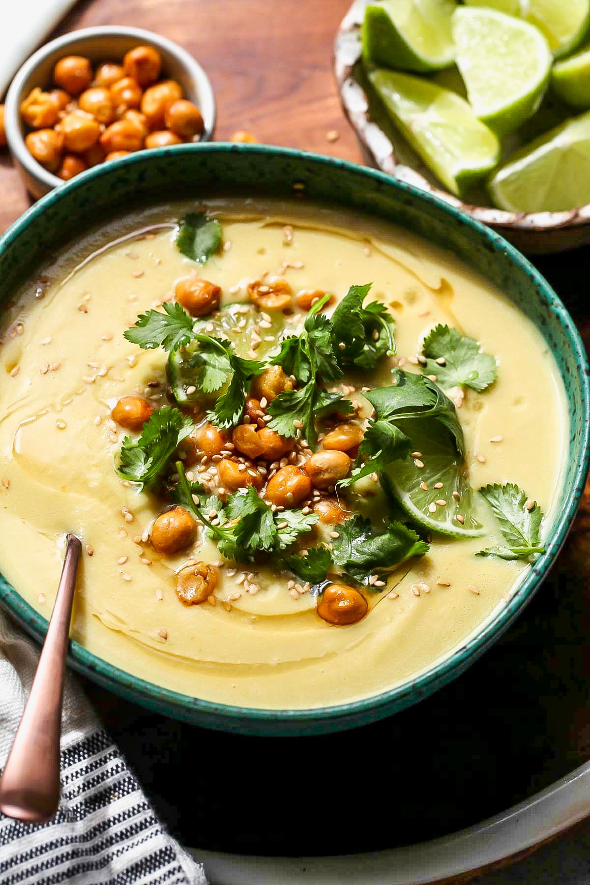 Curried cauliflower soup styled in a teal bowl with a spoon resting on the left side.