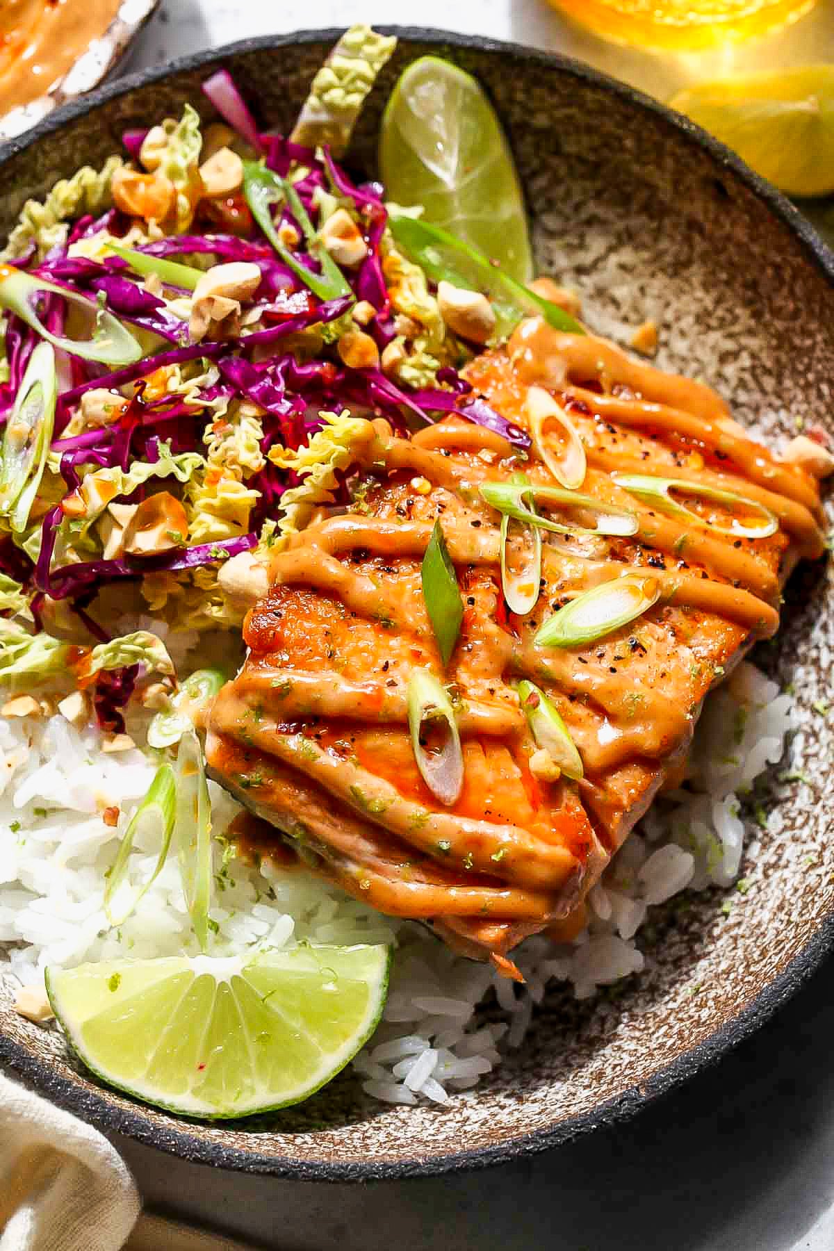 Firecracker salmon bowls styled in a grey bowl served with lime wedges.