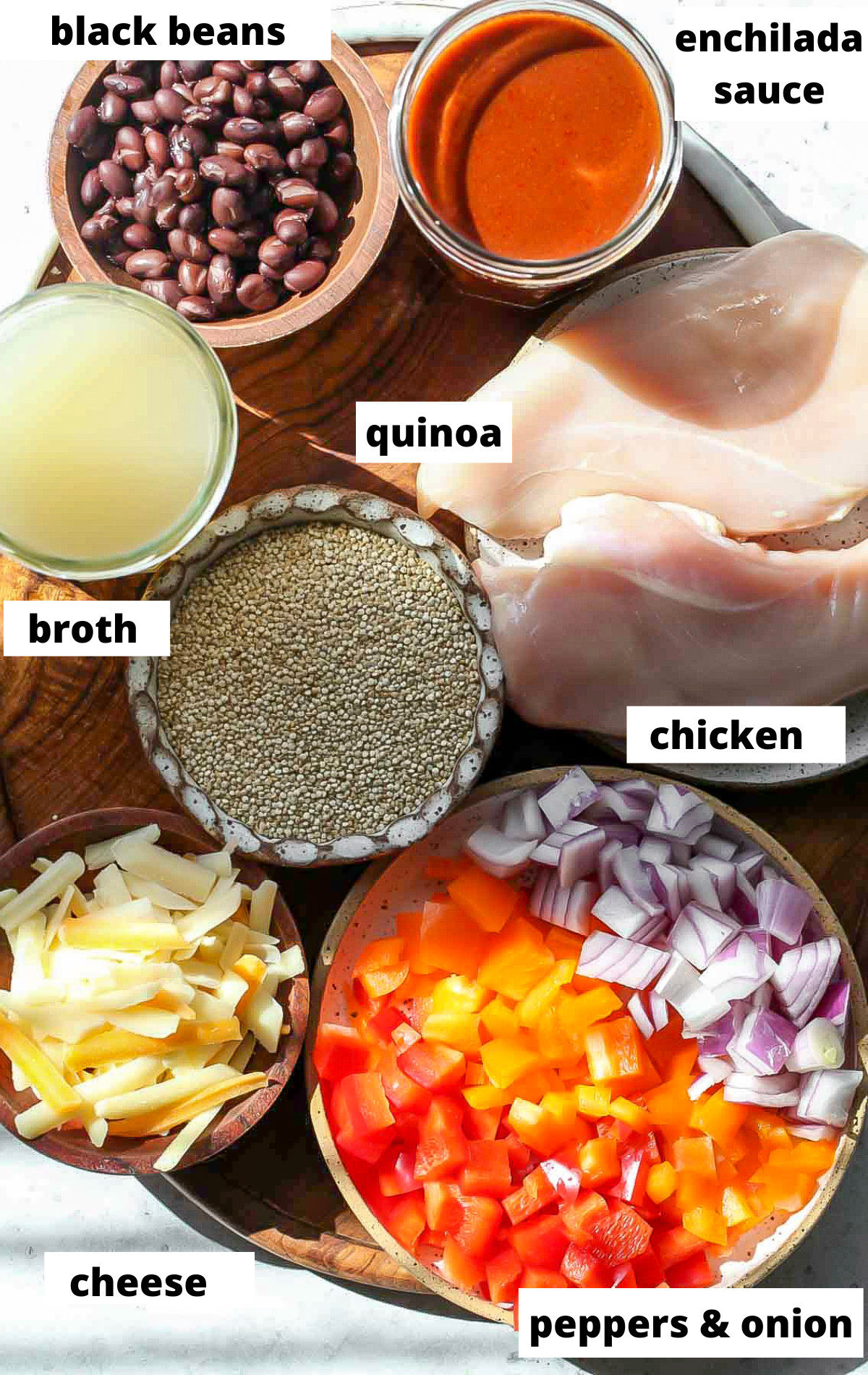 Recipe ingredients in bowls arranged on a wooden serving platter with labels.