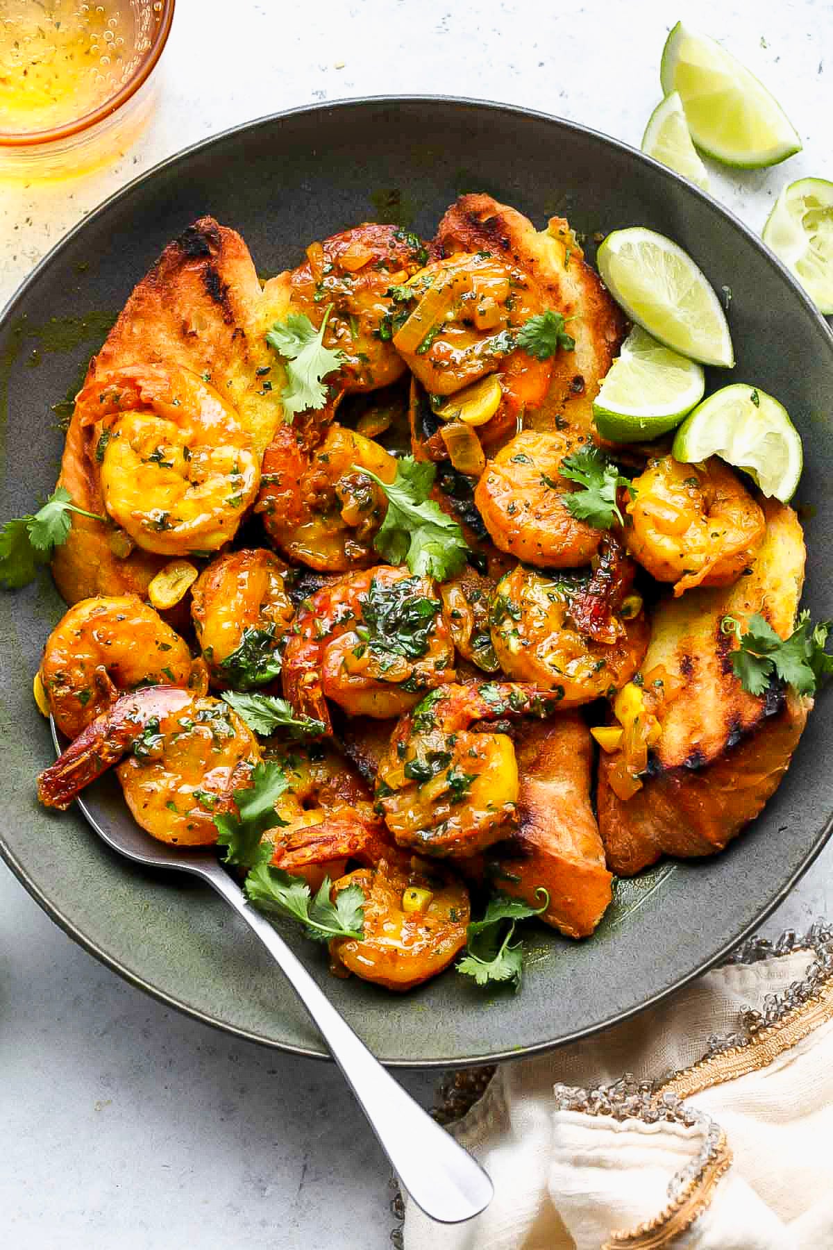Shrimp in turmeric sauce styled in a black bowl with grilled bread.