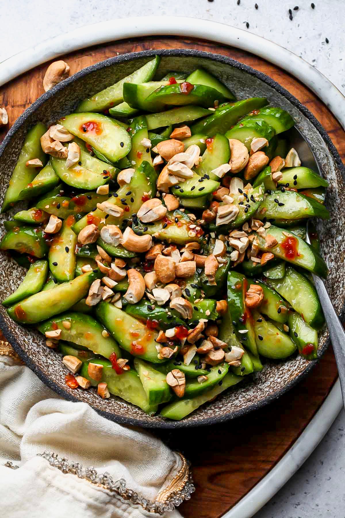 Asian cucumber salad styled in a bowl topped with chopped cashews.