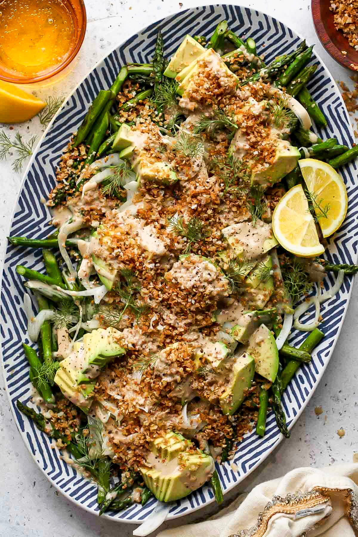 Asparagus avocado salad styled on a blue and white serving platter.