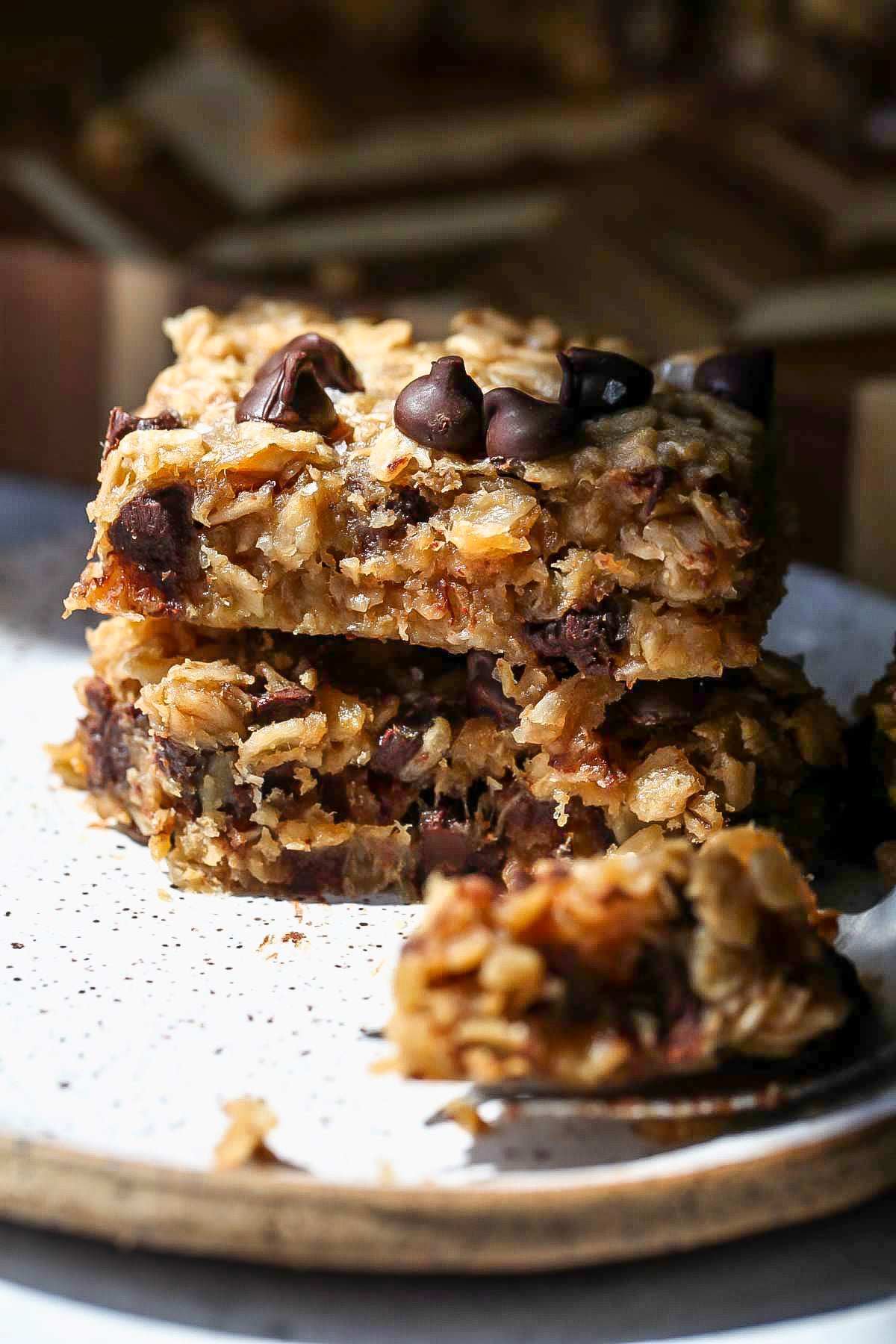Two oat bars stacked on top of one another with a fork taking a bite out of bottom bar.