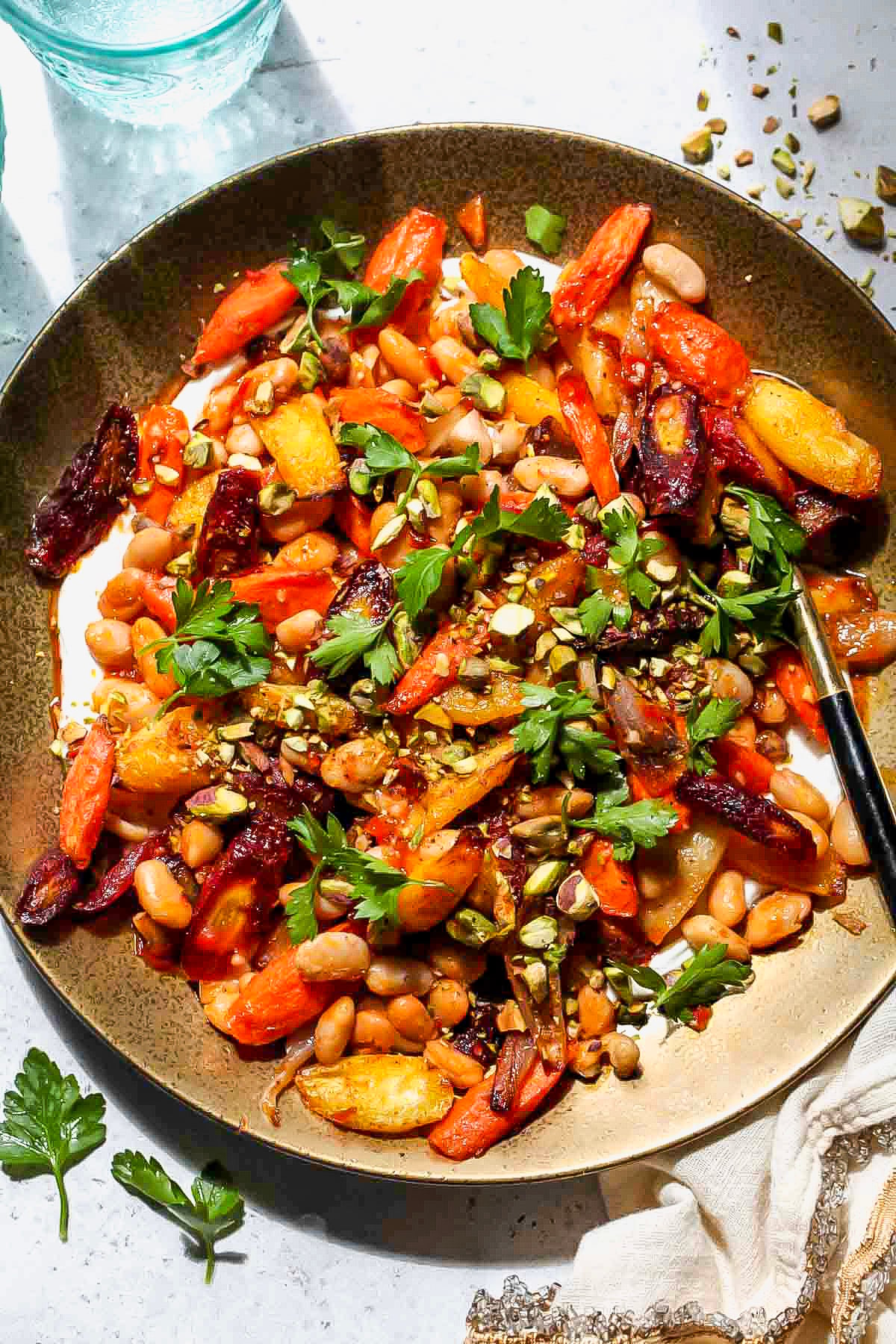 Roasted carrot salad with white beans and parsley styled on a gold serving platter.