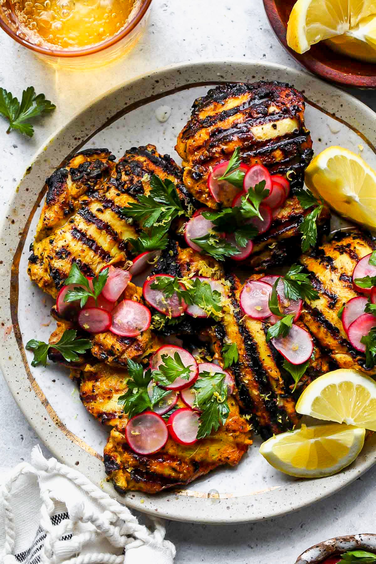 Turmeric chicken thighs arranged on a serving plate topped with radish salad.