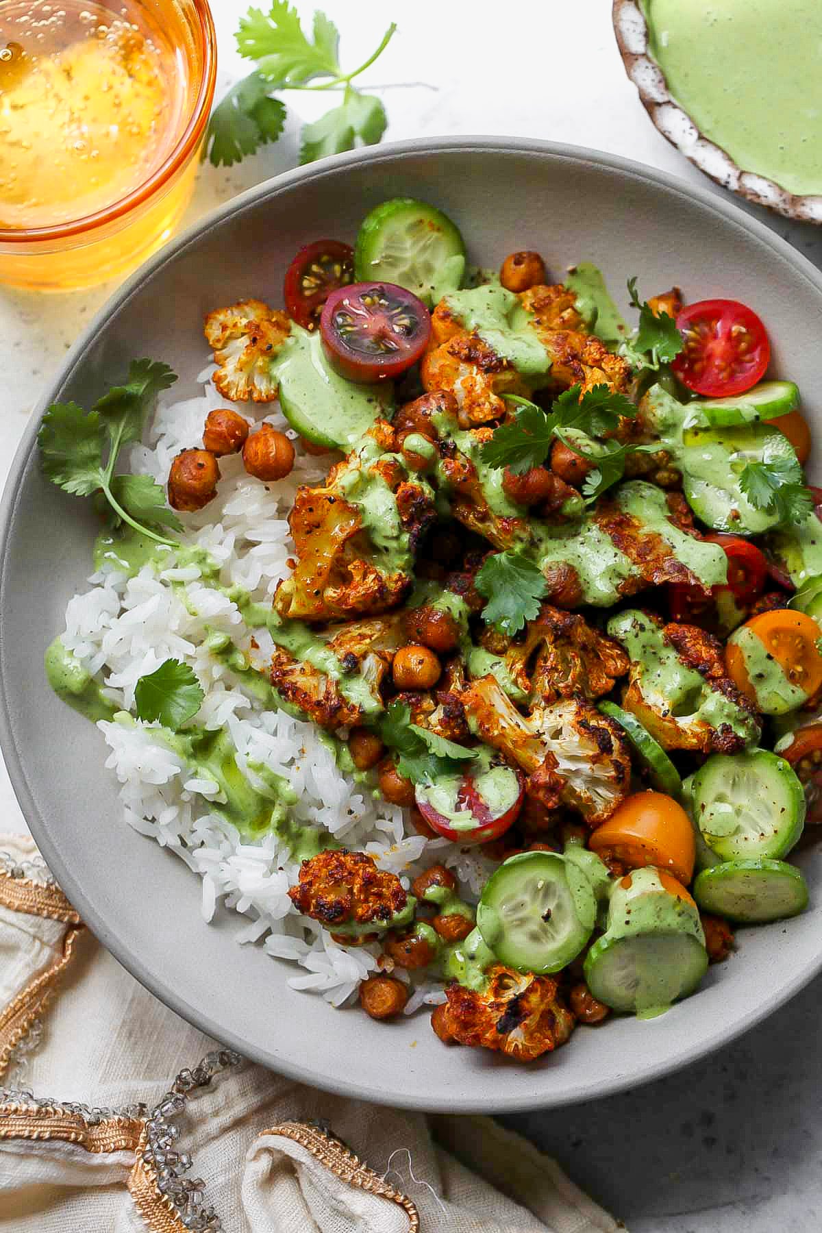 Cauliflower Shawarma Bowls topped with green tahini sauce in a grey serving bowl.