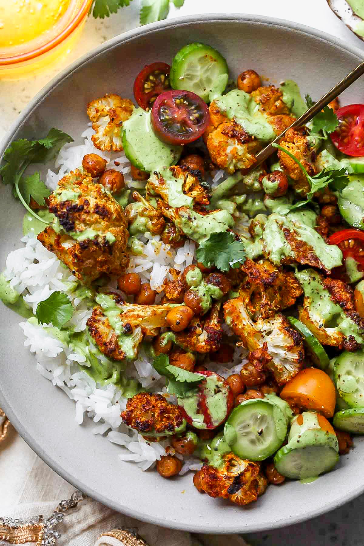 A fork digging into a bowl of cauliflower shawarma and chickpeas