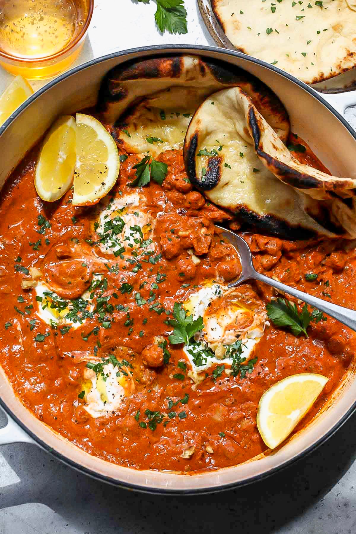 Muhammara Chickpea Skillet topped with naan and yogurt served in a white skillet.