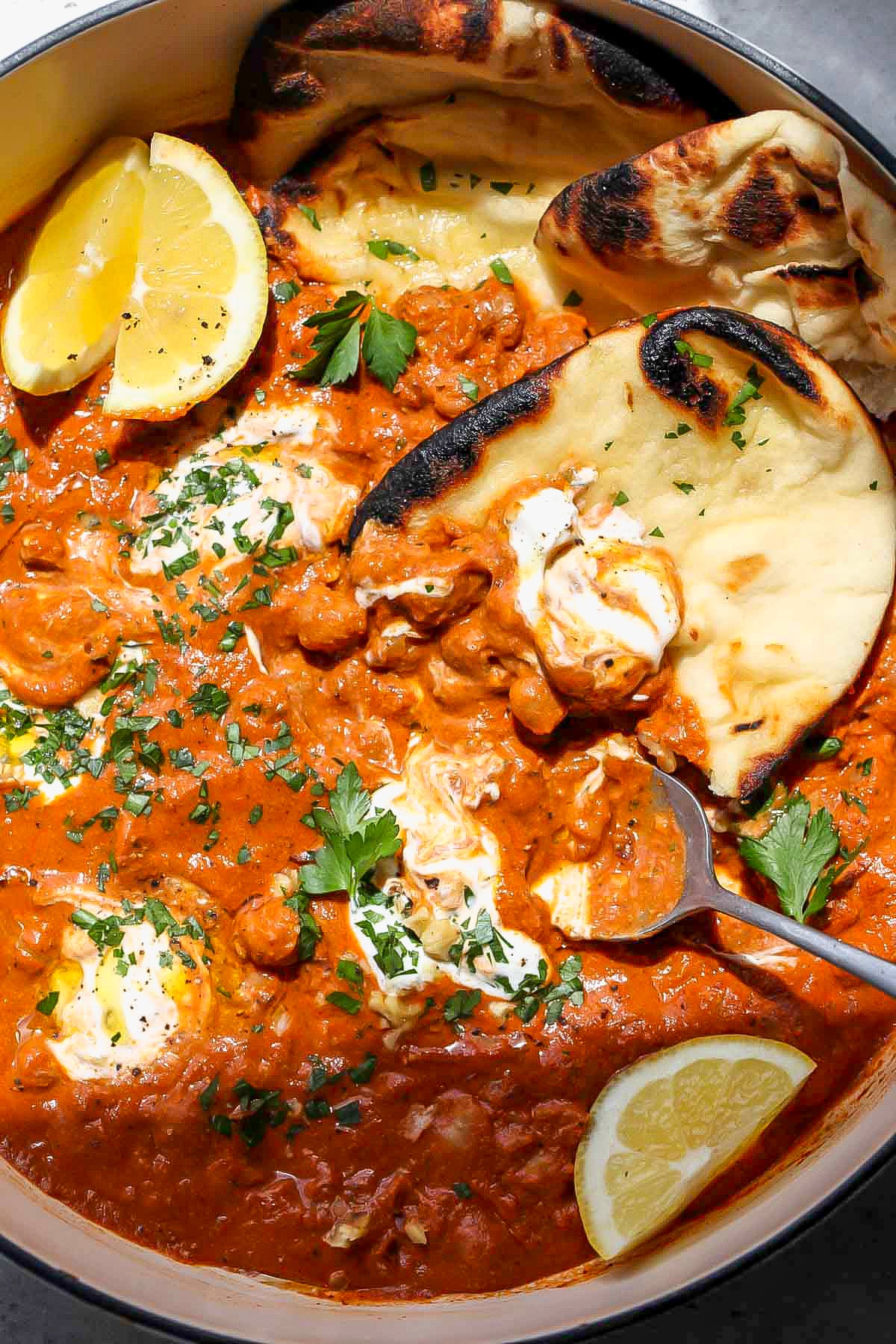 Naan bread scooping up chickpeas in sauce.